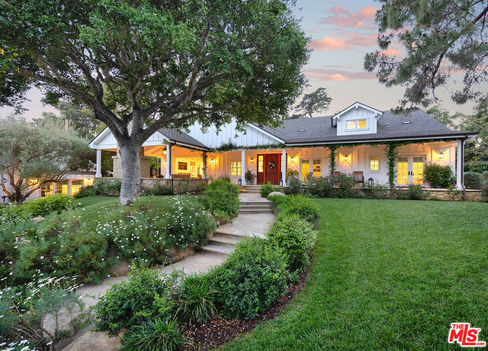 Dreamy architecture and classic design combine to create the ultimate storybook estate! Stone steps and whimsical wildflowers lead you to a romantic wrap around porch and a chic board and batten exterior, together embodying the spirit of the San Ysidro Ranch. Inside, an expansive great room hosts the family room, dining room, kitchen, and nook and exudes an effortless ease with an open layout and vaulted ceilings. Opening to patios on three sides, every moment is filled with light and air for an al fresco lifestyle. The primary is awash in crisp millwork and opens to a private spa and firepit. Together with the ADU and detached 3-car garage, this estate is a modern adventure in traditional living.