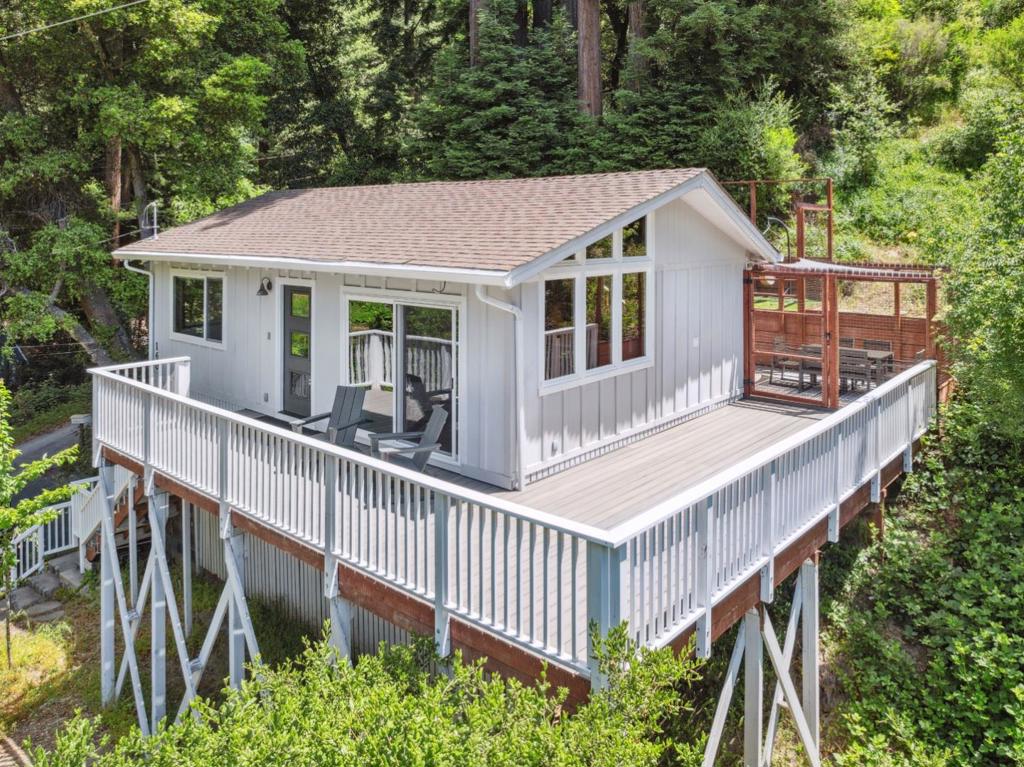Discover serene living in this charming home perched above a close-knit, well-kept neighborhood. Nestled among towering redwoods, the private backyard is perfect for summer hammock lounging or soaking up winter sun with stunning ridgeline views. Inside, vaulted redwood ceilings and a dramatic wall of windows frame the valley, creating a sense of peace and space. Watch fog roll majestically over the valley or bask in sunlight streaming through the south-facing windows. Thoughtful design includes leafguard gutters, a spacious Trex deck, LVP flooring, and low-maintenance astroturf, making outdoor living effortless. The expansive deck is perfect for entertaining or simply unwinding in your own private retreat. Excellent location with easy access to downtown Boulder Creek and all that it has to offer, including grocery stores, delicious restaurants, nightlife, and more. Experience tranquility, privacy, and community all in one place.