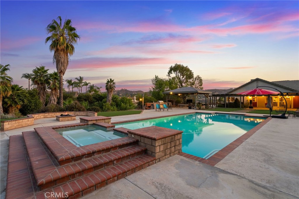 CANYONVIEW ESTATES-WOODCREST- A stunning single-story retreat nestled in the tranquil landscapes of a quiet countryside. This graceful home offers a seamless blend of modern luxury and natural beauty, boasting breathtaking views of the surrounding hills and the iconic Riverside scenery.
Spanning 2,698 square feet, this residence comprises four generously sized bedrooms and three well-appointed bathrooms with a bedroom and bath that is apart from the other rooms allowing privacy for quest stays or multi-generational needs. The heart of the home is the chef's kitchen, meticulously designed for both functionality and flair, making it perfect for culinary enthusiasts. Including premium appliances of Viking™ & Dacor™ 6-sealed burners and several convention and gas options. Complemented by a formal dining room that adds a touch of elegance to every meal with an uplifting living area with a dual-sided fireplace, creating an inviting ambiance for entertaining or relaxation.
An expansive 1.07-acre lot is a haven for outdoor enthusiasts and entertainers alike. Enjoy a luxury pool and spa, perfect for unwinding on warm California days. For sports lovers, this property includes a Sport Court, for basketball, pickleball, badminton or the likes, horseshoe pit, cornhole court, potential separate access gate entrance for flat RV/toy/trailer parking in plentiful abundances. Do not overlook the fully paid 24 solar panels to ensure energy efficiency, enhancing the modern living experience.
Step outside to your private oasis featuring a luxury pool and spa, perfect for relaxing or entertaining. Additional opportunities to consider include horse property with A11 zoning, multiple positions for an ADU placement, corner lot, amenities such as a wet bar indoors, and the outdoor kitchen with all the entertaining conveniences of a sink, built-in BBQ, a gigantic custom pavilion, gas fire pit with seating area for family fun that will bring a lifetime of memories with the gift of togetherness. There is so much more like a new washer/dryer set, recent re-plumb, stainless fridge and updating throughout--the list goes on and on.
Come and experience the serenity and luxury of 15725 Terraceview Court, where every detail has been thoughtfully designed to offer an unparalleled lifestyle in the lovely county of Riverside.