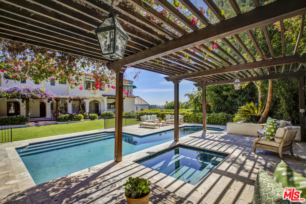 Landmark Los Feliz Estate | c. 1927 | Spanish Colonial Revival. Leave the city behind and enter a world of timeless elegance through an enchanting Mediterranean courtyard that beautifully unfolds like a secret garden. Graceful arches and colonnades, hand-crafted Moroccan lanterns, the scent of citrus trees in bloom, and the soothing sound of an Andalusian fountain joyfully welcome you to this architecturally significant Spanish Revival masterpiece. Designed by esteemed "Adobe Architect to the Stars" John William Chard, this 4-bed, 3.5-bath estate exudes a rich Hollywood provenance and undeniable mystique, its rare & authentic details seamlessly restored and enhanced with modern luxury & comforts. A dramatic 2-story entry leads to a grand scale step-down living room with soaring 17-foot beamed ceilings and a centerpiece fireplace. An adjacent library/media room opens effortlessly to the large flat, grassy yard, swimmer's pool, spa, citrus orchard, and a grapevine covered pergola, perfect for alfresco dining and impromptu soirees. The formal dining room leads to an Epicurean eat-in kitchen with Sub-Zero and Wolf appliances, soapstone counters, full pantry, and sunny breakfast room open to the courtyard. Upstairs, a spacious primary retreat with a separate sitting area and separate office or nursery framed by jetliner views of the Downtown LA skyline. Two additional guest bedrooms feature private balconies overlooking lush hillsides, while a secluded fourth bedroom suite accessible through the garden offers the perfect space for extended guests, a gym, or a home office. Awash in brilliant natural light, the home showcases Chard's signature touches throughout: thick, beautifully plastered walls, softly curved corners, artistic ironwork, graceful arches, tiles, and warm quarter sewn-oak floors. Ornate casement windows with antique hardware and wavy glass panes frame lush greenery from every room, enriching the home's timeless appeal. A premier Los Feliz address above the boulevard and an irresistible setting designed for unforgettable gatherings make this historic estate a true celebration of inspired living.