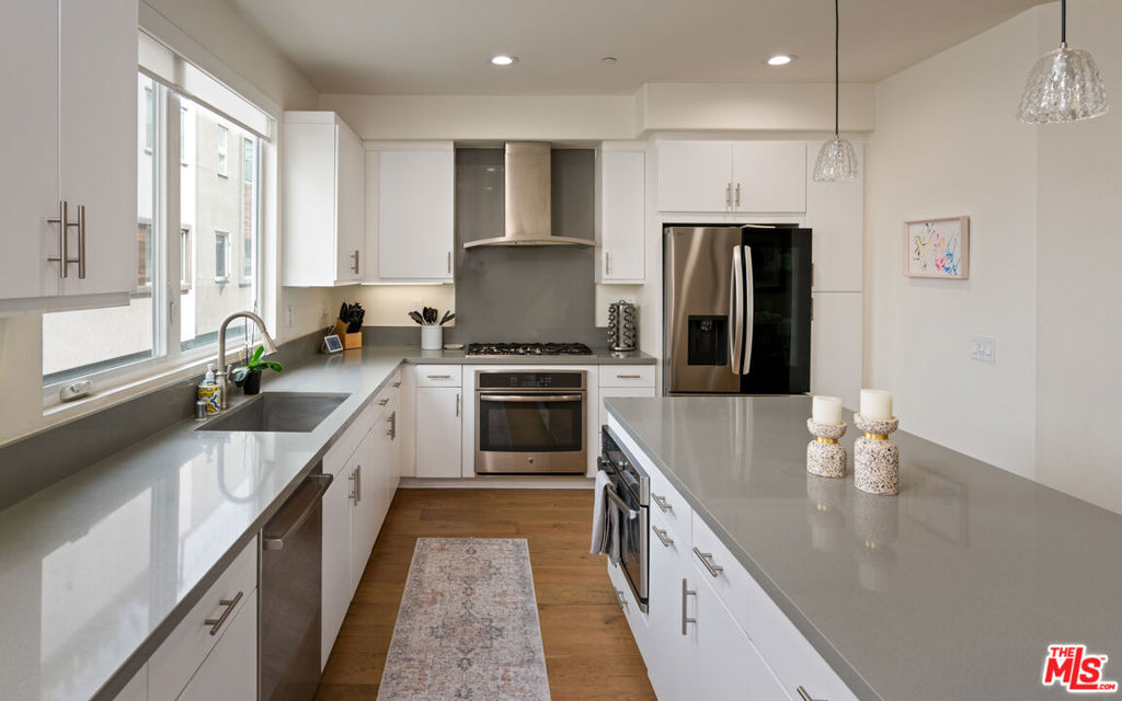 This contemporary retreat in Hancock Park, built in 2014, offers modern living just moments from the charm and convenience of Larchmont Villageone of the city's most coveted neighborhoods. Set within a secure gated community, this residence offers both privacy and unmatched accessibility. Designed with light, volume, and flow in mind, the 3-bedroom, 3.5-bath home offers 9-foot ceilings, windows on both ends for maximum light, and a private rooftop deck with sweeping 360 views of the Hollywood Sign and Downtown Los Angeles.The ground floor welcomes you with direct entry from a private two-car garage, alongside a flexible bedroom or office space ideal for guests or work. The second level unveils an open living and dining space, centered around a sleek chef's kitchen with custom cabinetry, premium countertops, and top-of-the-line appliances entertainer's dream framed by natural light on both ends. The third floor features two en-suite bedrooms and a dedicated laundry room, with the primary suite designed as a sanctuary: a generous walk-in closet, dual vanities, and a spa-inspired shower, evoking a sense of daily luxury. Crowning the home, the expansive rooftop patio transforms into an elevated lounge and dining space, a rare offering for hosting under the Los Angeles skyline. The HOA community offers guest parking as well as a common pet area. This is a residence that balances design, comfort, and an extraordinary location urban retreat that redefines modern city living.