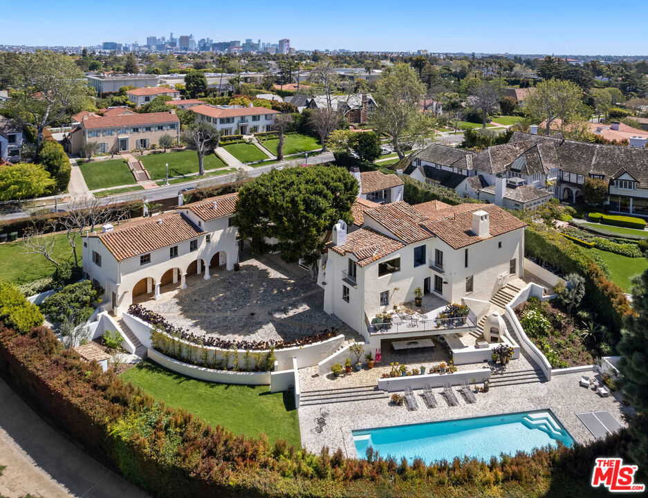 Introducing the Howard Hughes Estate, an iconic Spanish Revival masterpiece nestled along the 8th green of Wilshire Country Club. Situated on the prestigious South Muirfield Road in Hancock Park, this architectural gem is steeped in history and adorned with timeless elegance. Originally envisioned by renowned architect Roland E. Coate for socialite Eva K. Fudger, this estate later became the residence of legendary billionaire, movie mogul, and aviator Howard Hughes. Spanning 10,179 square feet, this residence seamlessly blends classic charm with contemporary luxury living. Every detail of this captivating property has been carefully considered, from luxurious finishes to tasteful accents throughout. As you enter through the gated driveway, you're greeted by a grand motor court leading to a spacious 3-car garage and workshop. The chef's kitchen features polished brass countertops and a magnificent 24-foot island, flowing into a voluminous family room adorned with floor-to-ceiling bookshelves and separate bar. The primary bedroom offers breathtaking views of the iconic Hollywood Sign and the sprawling fairways of Wilshire Country Club, enveloping you in old Hollywood glamour. With seven other beautifully appointed bedrooms, each offering its own unique blend of comfort and style, this estate provides ample space for relaxation and rejuvenation. An enchanting cobblestone courtyard with an outdoor fireplace serves as a tranquil retreat for both intimate relaxation or entertaining a hundred guests. Step outside to the expansive backyard, an entertainer's paradise complete with multiple lounge areas, a catering kitchen complete with a custom-built stone pizza oven, and a sparkling swimming pool with separate spa. Additional highlights include an intimate screening room, a 2,500-bottle wine vault, and a guest residence with a full kitchen and bath. Surrounded by meticulously landscaped grounds offering lush greenery and panoramic views of the Hollywood Hills, this estate holds a coveted place on the National Register of Historic Places and is designated as Los Angeles Historic Cultural Monument #1123. Don't miss this unparalleled opportunity to own a piece of Los Angeles history.