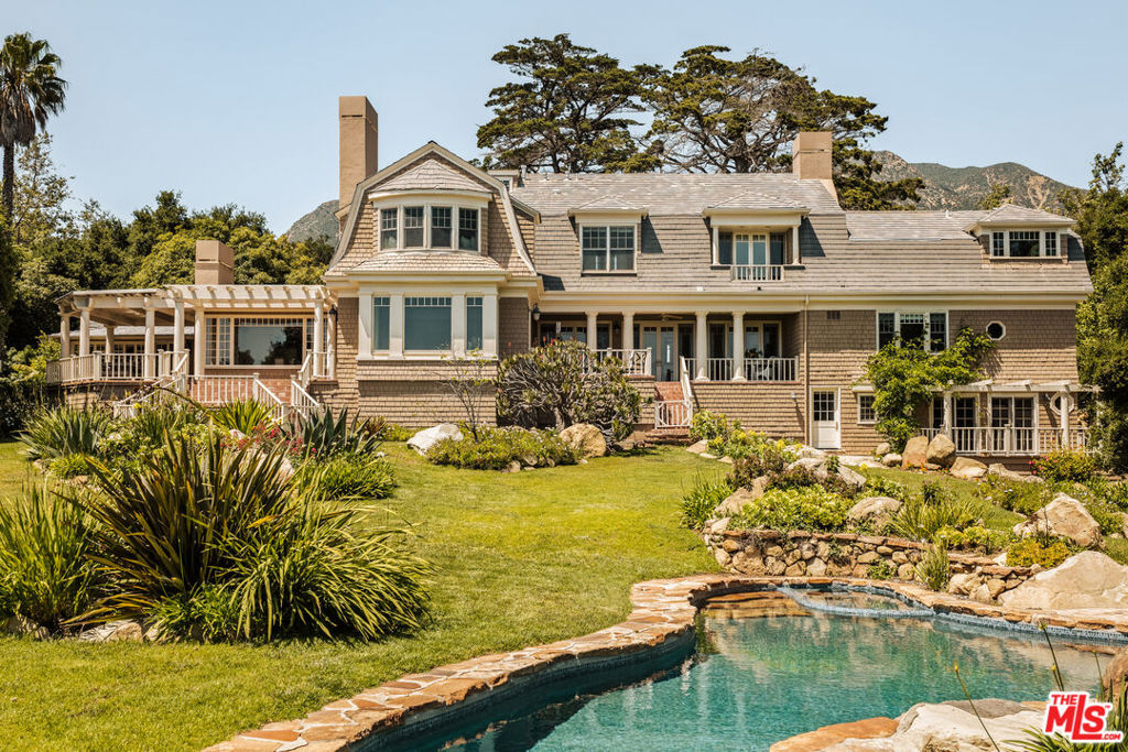 Welcome to Lilac Manor, a stately Cape Cod home nestled on Montecito's most coveted street. This magnificent estate is set on 2.04 acres of fertile soils with private walking trails, a dry rock creek, and incredibly well-maintained gardens filled with mature trees and rare plants that bloom year-round. Step across the motor court into the grand foyer with inlay hardwood floor, you will be greeted by an elegant living room with breathtaking views of the manicured grounds to the ocean and islands beyond. The living room offers soaring double height ceilings surrounded by a library on the upper level for cozy lounging or quiet reading. Oversized French windows and doors perfectly frame the tranquil gardens, offer an abundance of natural light, and provide a seamless flow to the covered porches outside. The well-appointed floor plan offers grand-scale public rooms, with handcrafted millwork and stunning red oak floors throughout. The open kitchen is equipped with top-of-the-line appliances, including a double-wide Gaggenau fridge/freezer, a huge center island with natural quartzite countertop, and overhead skylights. It opens directly to the formal dining room and family room - perfect for entertaining. The primary suite occupies an entire wing on the second floor and is outfitted with a beautiful sitting area with fireplace and private ocean-view balcony, a dressing room with wet bar, and dual walk-in closets and bathrooms. Two additional ground floor bedroom suites and a lower-level office/recreational area complete the main residence. Outside, the verdant gardens boast a variety of amenities and luxuries, including a charming storybook one-bedroom cottage, and a studio apartment above the garage with private driveway. Additional outdoor amenities include a sparkling crescent-shaped pool with built-in spa, entertainment decks, and an outdoor kitchen under a wisteria-covered dining pergola. Meandering paths lead you through lush plantings and tree canopies to the lower level with a tree house, vegetable bed, secret garden in the woods, and the dry creek. Hidden from the road behind mature vegetation, Lilac Manor's privacy is assured with three gated entries and its location on a peaceful lane tucked away in Montecito. Conveniently situated near Montecito Upper Village shops, restaurants, and Birnam Wood Golf Club, this estate offers serenity with breathtaking ocean vistas and is a true garden lover's paradise.