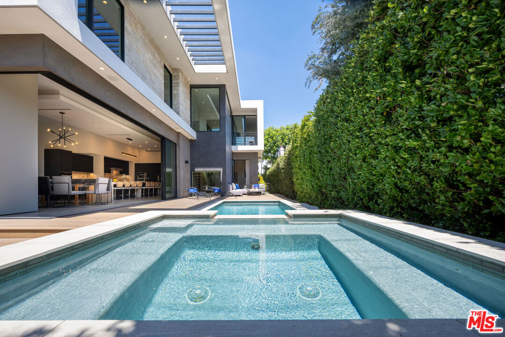 A custom built Modern home featured in Dwell and Haven that raises the bar with quality construction you can see and feel. Excellent fit and finish, unique features and beautiful Architectural details not commonly seen in homes outside of the Hollywood Hills. Refined scale throughout with soaring ceiling heights, timeless high-end luxury finishes and great attention to detail. The main level flows seamlessly to expansive outdoor patios, decks and swimming pool through walls of glass that disappear into the structure; accommodation for large gatherings. Strategically placed vertical and clerestory windows take advantage of year round natural light on the desirable south side of 4th St. Chef's kitchen with top-of-the-line Miele appliances, Quartzite counters and Arclinea custom cabinetry. Large dining area plus seating for eight at the huge kitchen island complete with Wine Cooler, second sink, pop-up outlets and lots of extra storage space. The top floor consists of an open view hallway connecting two large ensuite bedroom retreats with a third ensuite bedroom in-between. The primary features a modern flush mount gas fireplace, luxurious custom closet with center island and a spa style bath that has floor to ceiling windows and tile, free-standing tub, floating wall-to-wall double vanity, shower with room for two and a separate water closet. Extending outside, there's a south facing Juliette balcony with cityscape and backyard pool views plus a north facing treetop and mountain view rooftop deck over the garage with soft surface grass on almost 250sf. The lower level offers flex-space with high ceilings and natural light; fully equipped for entertaining, work, extended family, live-in help..or for simply having separation from the main level. There's a wet bar, dining area, several bedroom / bath options and room for a home theater, private screening room, recording studio, home business, offices, a kids nirvana, etc. The outdoor setting offers privacy and security with walls, gates and tall trees overlooking the sun-drenched heated pool, party-size hot tub with waterfall, all surrounded by lush mature landscaping which create an inviting atmosphere. Understated curb appeal with parking for two in the driveway and two in the direct-access garage that features high ceilings with room for storage; street parking at night is permit-only. With its central location in Beverly Grove-West, 8356 W 4th is poised to be a generational property designed to stand the test of time. Just blocks to the Beverly Center Mall, World Class Cedars Sinai Medical Group, Robertson Blvd's Shopping and Dining, 3rd Street and minutes to Beverly Hills, The Grove, West Hollywood and The Sunset Strip; restaurant, bar and shopping hot spots in every direction. Pedestrian & Pet friendly with walkscore.com at 91. House Taped by a CA Licensed Appraiser.