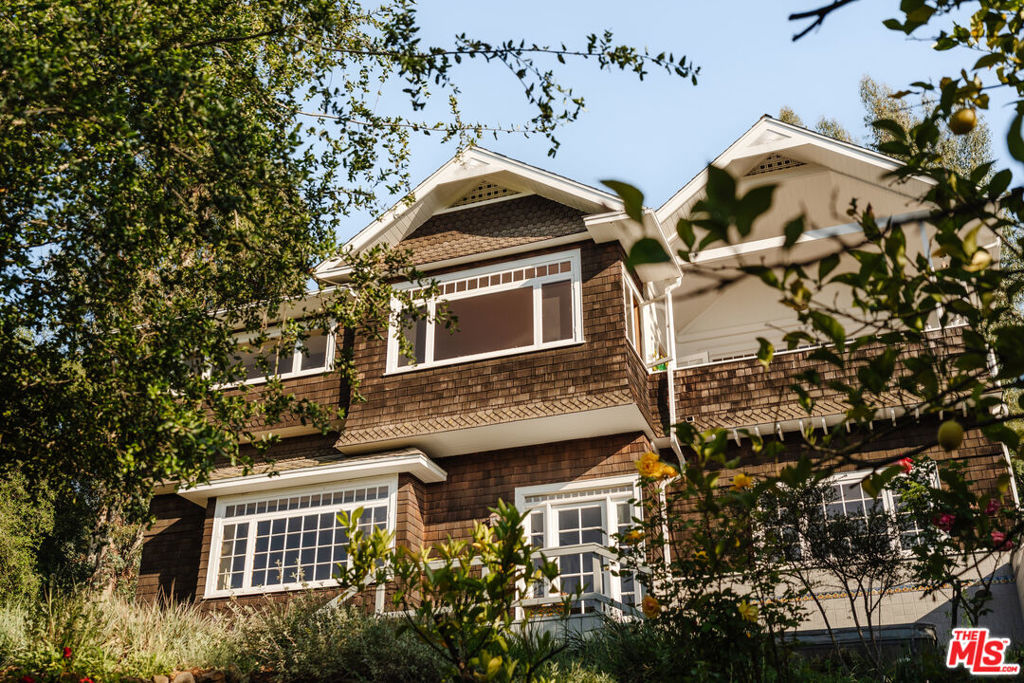 A Timeless Craftsman with Expansive Views and Natural Flow. Set on a quiet, neighborly street in Topanga, this 4-bedroom, 3.5-bath Craftsman-style home offers privacy, space, and panoramic canyon views from nearly every room. Situated on a double lot with native landscaping and seasonal blooms, it feels both connected to nature and comfortably removed from the pace of the city.An inviting front porch leads into the main level, where light flows through clerestory windows and large picture windows frame the surrounding greenery. The living room centers around a slate and oak fireplace, with an adjacent study providing a quiet space to read or work.Beyond the living area, the kitchen and dining room open toward the views, with warm red oak cabinetry, built-in storage, and a subtle art-deco feel. A walk-in pantry and built-in desk add function, while the sunset-facing deck just off the dining room is ideal for relaxing or entertaining outdoors. From here, the property's elevated position offers unobstructed views across the canyon.A staircase leads down to the private bedroom level, which stays naturally cool and quiet. A wide hallway opens into a casual sitting area, perfect for slower mornings or evening downtime. The primary suite features soft northern light, sunrise exposure, a walk-in closet with dressing area, and a spacious en suite bath. Two additional bedrooms share a bathroom and look out over the garden, while a fourth bedroom has its own bathroom and private exterior entrancewell-suited for guests or a home office.Outside, a lower deck includes a built-in hot tub and outdoor shower. Meandering paths connect shaded seating areas and open garden spaces, all planted with native, drought-tolerant species that bring color and texture year-round.Thoughtfully designed and well maintained, this is a home that offers space, calm, and an easy connection to the landscape around it.