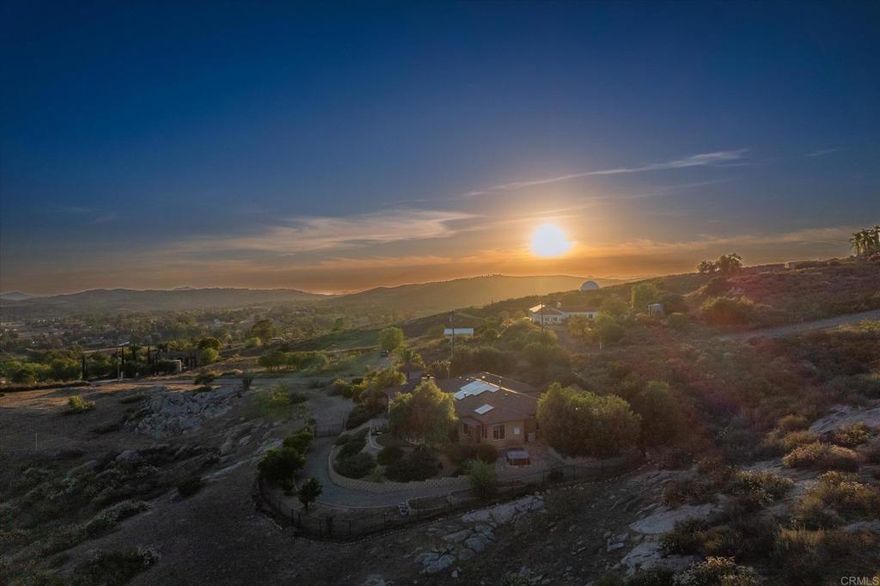 Experience luxury, privacy, and timeless design in this exceptional hilltop retreat in Ramona. Designed by acclaimed architect Carole Wylie, this contemporary Craftsman-style residence showcases breathtaking 270° panoramic mountain and valley views from nearly every room.  Boasting 2,496 square feet of thoughtfully designed living space, this home offers 3 bedrooms plus a dedicated office (optional 4th bedroom) and 2 elegant bathrooms. The heart of the home is the chef’s kitchen, featuring custom cabinetry, travertine flooring, and high-end KitchenAid appliances—including double convection ovens, a 5-burner cooktop, built-in refrigerator, and water filtration system. The open layout flows seamlessly into the dramatic great room with 12-foot ceilings, exposed wood beams, and a striking stone fireplace.  Natural light floods the home through oversized picture windows and multiple sliding doors that lead to a series of private patios—ideal for entertaining or relaxing in total solitude. The formal dining room includes built-in china cabinetry and endless views that elevate every gathering.  The primary suite is a serene escape with its own fireplace, a luxurious spa bathroom with freestanding soaking tub and walk-in shower, and direct access to a private patio with hot tub—perfect for stargazing.  Modern upgrades include a fully paid solar system, 10kW backup generator with automatic transfer switch, EV charger, and a spacious three-car tandem garage with epoxy floors, built-in storage, and a dedicated workshop.  Outside, the home continues to impress with fully fenced grounds, citrus trees, raised garden beds, RV parking with hookups, a 10,000-gallon water tank, and a cleared pad ready for an ADU, barn, or shop—offering endless future potential.  This property isn’t just a home—it’s a lifestyle. Whether you're seeking privacy, sustainability, room to grow, or simply a stunning place to call your own, this one-of-a-kind retreat delivers.
