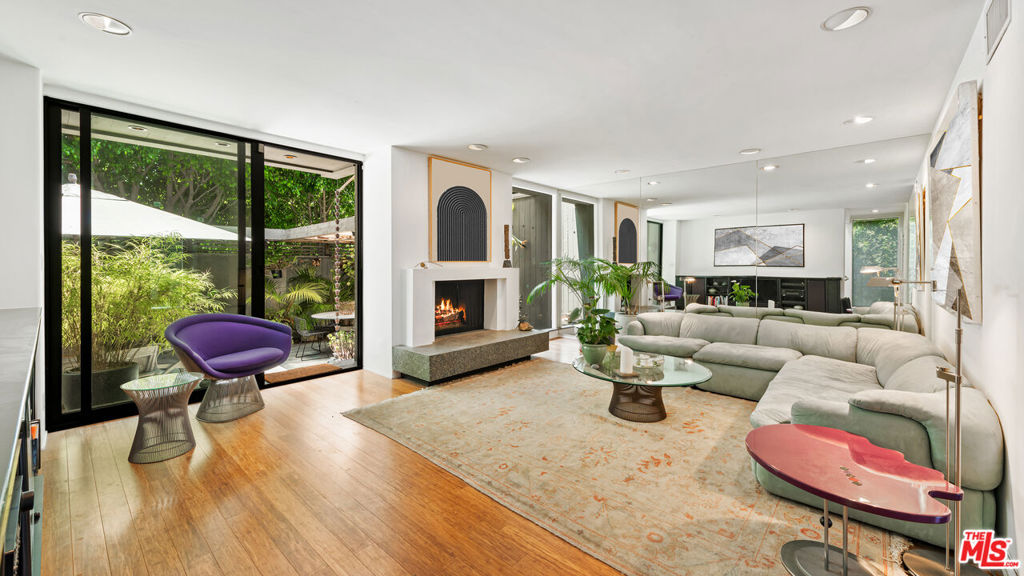 Located in a prestigious enclave, this sophisticated coastal condo offers refined living with every modern convenience. A private community pool and exterior camera system provide peace of mind and an elevated lifestyle. The entry welcomes you with stone tile floors and a mirrored accent wall, setting a polished tone. Ascend the stairs to the main living floor where curated details and natural textures define the space.The powder room features stone counters, a modern sink, and a sleek vanity. Just ahead, the living room boasts warm wood floors, a fireplace with a stone hearth, recessed lighting, and sliding glass doors that open to a private patio. Ideal for seamless entertaining, the adjacent dining area features additional built-ins and a stone sideboard. A nearby wet bar includes granite counters, a sink, wine storage racks, and ample cabinetry, perfect for hosting.The chef's kitchen is thoughtfully appointed with granite counters, a four-burner range, Gaggenau oven and hood fan, Miele dishwasher, and Liebherr fridge and freezer. A sliding glass door opens to a tranquil seating area with a fountain, enhancing the indoor-outdoor flow. The Nest smart thermostat system adds intuitive climate control throughout.Upstairs, the first landing offers convenient built-in storage. The expansive primary suite impresses with carpeted floors, soaring wood-beamed ceilings, a fireplace, and a large sitting area with built-in shelving and a TV. A secondary closet includes a built-in bar and mini fridge, while the large wardrobe features custom built-ins. The primary bath includes a high skylit ceiling, stone details, a spacious shower stall, and a refined vanity with built-in storage.A secondary bedroom also includes closet space with mirrored doors, built-in drawers and shelves, and a sliding wood door leading to a luxurious en-suite bathroom with stone counters, a makeup vanity, and a shower over tub.The private patio extends the home's appeal with stone tile floors, a partial cover, a built-in music system, an outdoor fireplace, storage, and a charming fountain. Additional amenities include central air and heat, a mudroom/laundry area with stacked Miele units, and a two-car garage with ample storage. This condo is a true turnkey sanctuary in a coveted coastal setting.