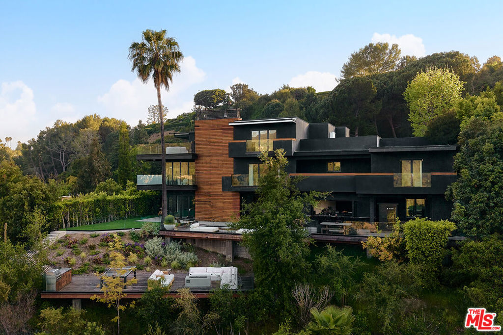 Architectural Digest Featured Brentwood Estate with Ocean and Canyon Views. Set on a breathtaking verdant lot, this 7 bedroom, 10 bathroom masterpiece offers the perfect blend of refined design, natural beauty, and ultimate privacy. Designed with indoor-outdoor living in mind, the home is surrounded by lush greenery and opens to sweeping ocean and canyon views. Expanses of glass, natural materials, and soaring windows invite an abundance of light and a sense of calm throughout the home. Every room connects effortlessly to the outdoors, with multiple entertaining spaces, tranquil patios, and a seamless flow that captures the essence of California living. The Chef's kitchen stuns with top-tier appliances, sleek modern lines, and bold designer details equally suited for intimate mornings or lively entertaining. Retreat to the primary suite where you'll find a spa-like bathroom, massive walk-in closet, private balcony, and curated details that evoke warmth and sophistication. Among the standout amenities are a moody, luxe speakeasy game room, a wellness/gym room, a 1,000-square-foot rooftop deck, and dynamic spaces that cater to both vibrant entertaining and tranquil living. Whether hosting grand events or seeking quiet reprieve, every inch of this home has been thoughtfully conceived for those who expect the extraordinary.
