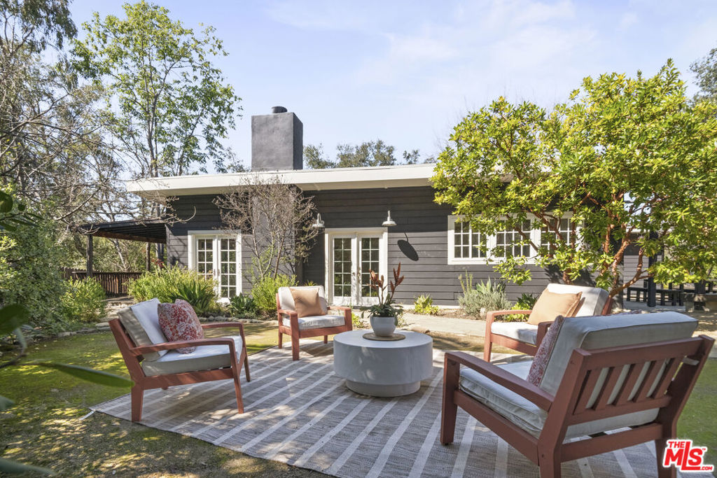 Find your peaceful place to abide in this four-bedroom, three-bath, contemporary cottage-style home with two separate guest suites. Situated on a usable third of an acre fenced yard, this home gives you room to entertain family and guests in a mini-compound designed for indoor-outdoor living. The huge kitchen anchors the living and dining rooms, with an open plan that allows guests to flow from the shaded view deck to the back patio. The primary suite is separate from the other three bedrooms, allowing privacy. Having so many bedrooms provides options for a great home office. The main house bonus basement room could be a home theater, a playroom, or an art studio. Your guests will enjoy their stay in either the separate studio guest house with its own view patio or the guest suite attached to the garage. Flat play areas are edged by grapefruit, lemon, lime, plum, and pomegranate trees. Plenty of parking in the garage and driveway. Close to Topanga State Park trails. Come up to the canyon!