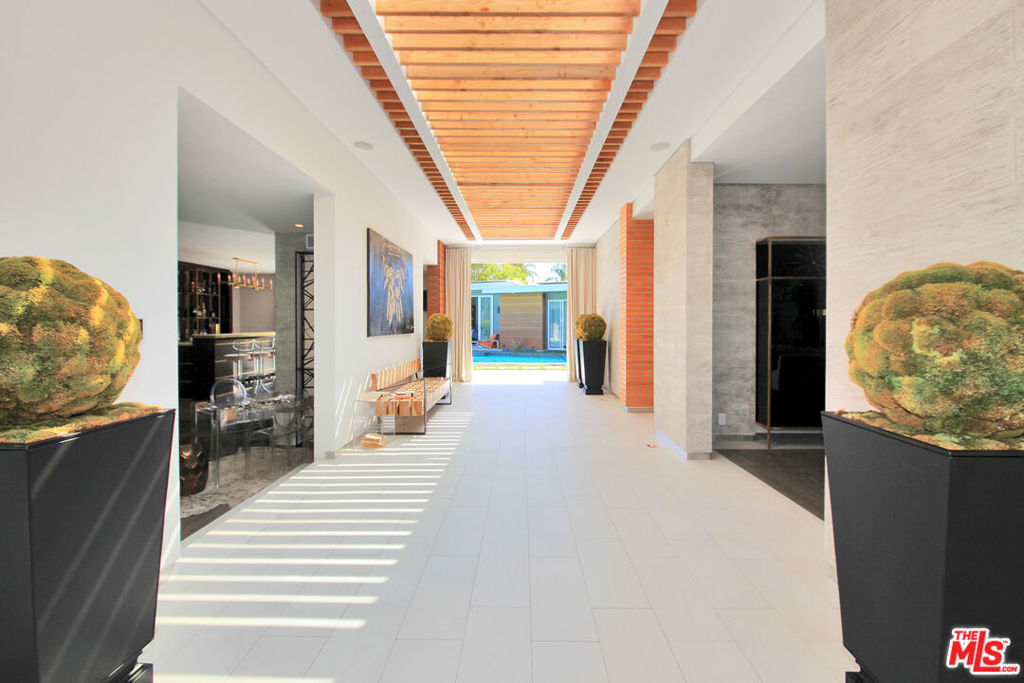 Nestled in one of Brentwood's most sought-after neighborhoods, this completely remodeled contemporary masterpiece blends luxurious design with effortless indoor-outdoor living. From the stunning grand formal entry, you're greeted with breathtaking sight lines to the sparkling pool and an abundance of natural light pouring through expansive glass doors and windows. The open floor plan boasts 4 spacious bedrooms and 4 1/2 spa-like bathrooms, including a serene primary suite with a generous walk-in closet. The chef's kitchen is a showpiece, featuring a massive center island, high-end stainless steel appliances, custom built-ins, and a skylight that floods the space with sunlight while framing views of the lush backyard. Perfect for entertaining, the private custom bar overlooks the pool, while multiple seating areas invite al fresco dining with views of the city lights and mountains. The resort-style backyard offers a sanctuary-like atmosphere, complete with seamless indoor-outdoor flow, manicured greenery, and an inviting pool deck. Additional highlights include soaring ceilings, recessed lighting, designer chandeliers, two elegant fireplaces, and meticulous custom finishes throughout. Every element of this home has been crafted to create a tranquil escape from the city's hustle and bustle. An ideal blend of sophistication and comfort in the heart of Brentwood. Pool is currently covered as owners have small children. Home can be delivered with the pool covered or with the pool open as shown in photos. Home can also be leased fully or partially furnished at a premium. Call to inquire.