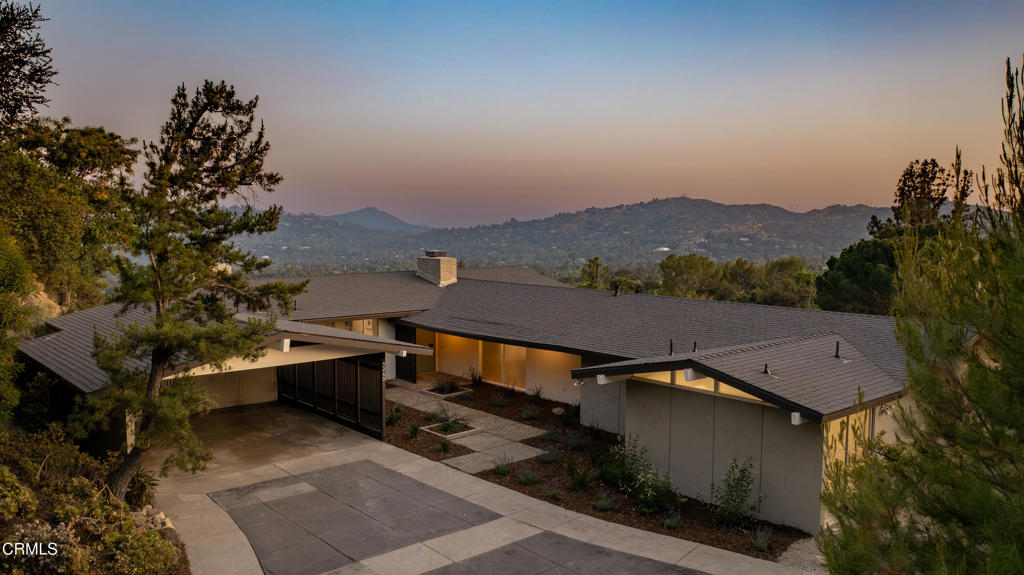 Offered for the first time in over 50 years, this classic mid-century gem is nestled at the top of Gould Avenue in a secluded & highly sought-after enclave of La Canada. Set high above the city on a quiet hilltop, this property boasts spectacular panoramic views & timeless architectural appeal. As you approach, clean lines & original mid-century details welcome you. The property evokes an immediate sense of calm & seclusion. The setting is peaceful & rare--homes in this part of La Canada seldom come to the market. As you enter through the front door, you're welcomed by tiled flooring & the unmistakable charm of a well-preserved mid-century floor plan. The spacious living & dining room is the heart of the home, featuring large picture windows that frame incredible panoramic views & a decorative corner fireplace with a raised tiled hearth. Natural light pours in from every angle, creating a warm & welcoming environment. This open space connects to a den, ideal for casual living or entertaining, which also features a decorative fireplace, parquet wood floors, a sliding glass door to the backyard & access to the kitchen. The kitchen offers new vinyl tile flooring, a new electric cooktop, ample cabinetry & a functional flow that connects to the laundry area, a side door to the carport & a powder room. Three bedrooms are on the opposite side of the home. A central 3/4 bath serves the first 2 bedrooms, complete with a tiled shower & a single-sink vanity. At the end of the hall, the expansive primary suite is a true retreat. Offering incredible storage with 4 closets plus a walk-in wardrobe, this room is designed for comfort. Large sliding doors provide direct access to a patio area & showcase the home's elevated views. The attached ensuite bathroom features a dual-sink vanity, a built-in makeup vanity, a soaking tub & a separate tiled shower. The backyard is a stunning natural extension of the home, offering a variety of peaceful outdoor living spaces framed by river rock pavers & multiple seating areas. Whether enjoying a morning coffee on the patio or entertaining guests beneath the stars, the backdrop is nothing short of breathtaking--sweeping vistas of the valley floor & distant skyline provide a daily reminder of the home's truly special location. This is more than just a house--it's a rare chance to restore, renovate, or reimagine a mid-century jewel in one of La Canada Flintridge's most exclusive & peaceful hillside neighborhoods.