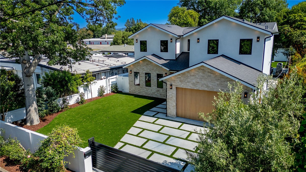 Gated Estate in the heart of Woodland Hills. Newly completed, this property is a rare blend of luxury, privacy---crafted with designer finishes, and sleek, modern materials throughout both the main residence and the legally permitted ADU (with its own address). Step inside the stunning main house to discover 9’10” high ceilings, surround-sound speakers, designer lighting, solid oak doors, Roman stone accents and wooden flooring. The chef’s kitchen features top-of-the-line Thermador appliances, porcelain countertops, immense pantry and other thoughtful storage solutions. With an open floor plan, the kitchen flows seamlessly into the living room (with a gas fireplace), and the dining that opens to the interior patio. Every modern upgrade has been considered: dual hv/ac systems with separate thermostats, solar panels, tankless water heater, EV wiring, new electrical & plumbing throughout. The primary suite is a retreat, featuring a private balcony overlooking the backyard, a cozy gas fireplace, a huge walk-in closet, and a spa-inspired bathroom complete with soaking tub and a luxurious dual-entry shower. All four bedrooms are ensuite; and the ADU offers an additional 2 bedrooms, 2 bathrooms, living room with electric fireplace, full kitchen and in-unit laundry. Step outside to enjoy the landscaped backyard--featuring a sprawling lawn, brand-new pool and spa, a fire pit, and a built-in outdoor kitchen. Nestled in a family-friendly neighborhood just moments from premier shopping and dining at The Village, Westfield Topanga, and Calabasas Commons; and zoned for top-rated El Camino Real and Hale Charter Schools.