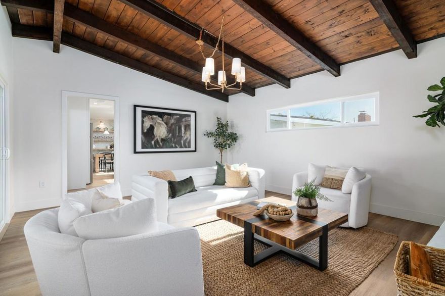 Beautifully reimagined single-level home in the heart of Serra Mesa, offering modern design, flexible living spaces, and seamless indoor-outdoor flow in one of San Diego's most centrally located neighborhoods.  The light-filled interior features warm flooring, clean lines, and multiple living areas, including a spacious family room highlighted by a dramatic wood-beamed ceiling, arched stucco fireplace, and sliding doors that open to the backyard—ideal for everyday living and entertaining. The open-concept kitchen is thoughtfully designed with quartz countertops, stainless steel appliances, and a built-in microwave drawer.  The primary suite provides a comfortable retreat with ample natural light and a beautifully updated ensuite bathroom, featuring a walk-in shower, designer tile, and modern finishes. Additional bedrooms are versatile and well-appointed, complemented by a stylishly updated secondary bathroom. Designer touches throughout include wallpaper, shiplap, custom millwork, and more.  The private backyard is perfect for enjoying San Diego's indoor-outdoor lifestyle, featuring a covered patio with deck, a generous lawn, and peaceful hillside backdrop. Conveniently located near freeways, shopping, dining, parks, and beaches, this move-in-ready Serra Mesa home offers a rare blend of style, comfort, and central convenience.