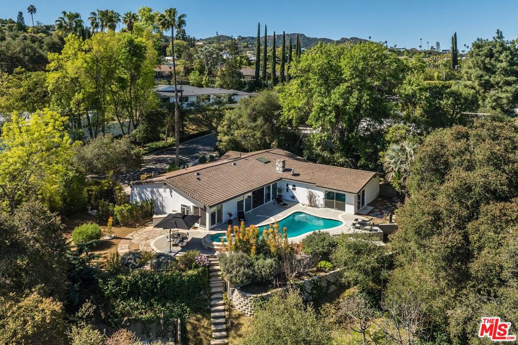 Nestled south of the Boulevard in the heart of Encino, this sophisticated and private Mid-Century modern retreat offers the ultimate California lifestyle. Step through the grand entrance into an airy, light-filled space where walls of glass seamlessly merge indoor and outdoor living. The inviting living room, complete with a sleek fireplace, flows effortlessly into the dining area, creating a perfect space for entertaining. The bright and spacious kitchen features abundant cabinetry and ample prep space, ideal for any home chef. The primary suite is a serene escape, boasting double glass sliders that open to the lush backyard, a walk-in closet, and a spa-like bath with dual vanities, a soaking tub, and a separate shower. Three additional bedrooms, each with generous closet space, share two full baths. Additional amenities include a stylish powder room for guests, a dedicated laundry room, and a two-car garage. Outside, the stunning backyard is a true showstopper, featuring a sparkling pool, spa, and a spacious patio, all surrounded by mature landscaping for ultimate privacy. Located within the highly acclaimed Lanai Road Elementary School district and just minutes from the premier shopping and dining along Ventura Boulevard, with easy access to the Westside this dream home is waiting for you!