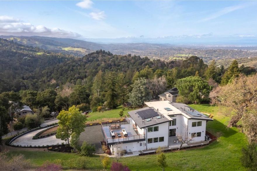 Just completed with final. Located in the posh town of Portola Valley this stunning rebuild offers space, views, and peace of mind. With completely new high-end finishes throughout, this Mid-Century Modern masterpiece sits atop a private, lush acre, seamlessly blending modern luxury with natures tranquility. Designed for those who appreciate both serenity and grand entertaining, a true retreat where hawks glide above and nature surrounds you. The expansive open-concept living space flows into a gourmet kitchen, featuring Bertazzoni five-burner gas stove, refrigerator and dishwasher plus gorgeous brass fixtures. Floor-to-ceiling windows showcase panoramic views of rolling hills & twinkling city lights, creating an awe-inspiring backdrop. A grand two-story entryway leads to an elegant dining area, warmed by a glass-enclosed gas fireplace. Step onto the rooftop deck, where alfresco dining meets unparalleled stargazing & sunset views. The primary suite is a private sanctuary, complete with a spa-like soaking tub and a bed perfectly positioned for breathtaking sunset views. Four additional bedrooms offer luxury & privacy for all, each has its own full bath. This new residence is more than a home. It's an experience of modern elegance, timeless design, & natures embrace.