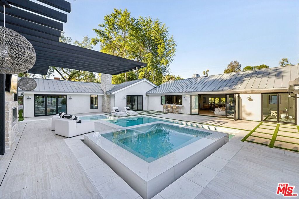 Stunning single-story in Hidden Hills! Luxury designer touches at every turn with a modern open floorplan full of natural light with bifold doors creating an indoor/outdoor flow. Gorgeous new pool and spa with natural limestone and a rain curtain water feature are perfect for entertaining and outdoor living. The spacious gourmet kitchen features white oak cabinets with gorgeous Calacatta Marble countertops, both Wolf & Sub-zero appliances, a 72-bottle wine cellar, an icemaker, and retractable bi-fold kitchen window opening to the outdoor serving bar. The great room, dining room, kitchen, game room and all bedrooms all feature ultra-wide white oak floors with a see-through limestone fireplace to the contemporary open dining room. There are five bedrooms (including two primary suites), all with stone baths. The primary suite is brand new as a part of the expansion to create a massive spa-like bathroom and walk-in closets. Additional features include all new windows & doors, all new electrical, new HVAC systems with smart-home climate controls, new plumbing, new natural gas fireplaces, new appliances, Control 4 smart-home system for audio/video and Wi-Fi, tankless water heater system, new paver driveway, new hardscape, new landscape and irrigation, and a new metal standing seam roof. The beautiful grounds include a resort style pool with natural limestone coping, LED underlit steps, and a large Baja shelf. The adjoining barbecue center features a 42" Wolf BBQ grill with Wolf accessories, a beverage fridge, and a polished concrete dining island. From start to finish, this is a one of a kind, designer luxury home.