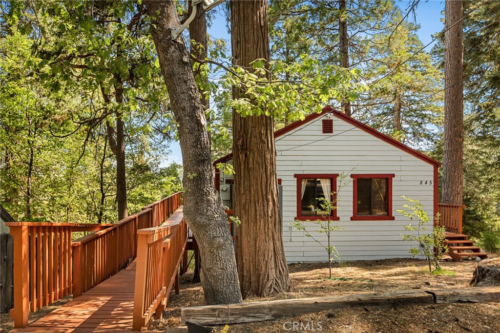 This charming mountain retreat offers comfort, privacy and LAKE VIEWS! Enjoy the ease of level entry, and one level living, in this two generously sized bedrooms, one bath, thoughtfully designed home that gives a tree house setting off the back decks. The large living room boasts the beautiful brick fireplace that helps to create a warm and inviting atmosphere for those Winter months. Enjoy the spacious, very large, partial wraparound deck featuring picturesque, ridgeline and lake views, creating an ideal setting for relaxing and entertaining. Set on a large, private lot, surrounded by towering trees and forest views this cabin is more than a home, it's a lifestyle. The down stairs buildup area should not be missed and has true potential to add on lots of sqfootage if desired. Sellers freshened the exterior and deck paint recently, and there is even a metal roof. The possibilities are endless, whether you're looking for a full-time residence or the perfect mountain escape, this property should not be missed. Property is being sold furnished minus sellers personals.