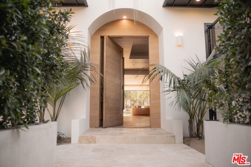 Discover a meticulously reimagined sanctuary where Tulum inspired elegance meets relaxed sophistication. Situated in the heart of Beverly Grove, this gated architectural masterpiece seamlessly blends modern design with effortless luxury. Spanning over 5,000 SF of indoor-outdoor living, the home features a gourmet kitchen with Miele and Leicht appliances, an oversized island, and pocket sliding doors that connect bright interiors to lush outdoor spaces.Featuring four spacious bedrooms and six luxurious bathrooms, this home includes a stunning primary suite with a cozy fireplace, a large private balcony, custom walk-in closets, and a sleek spa-inspired bathroom with a freestanding soaking tub. The second floor offers a charming outdoor terrace, leading to a rooftop deck complete with a built-in wet bar and breathtaking 360-degree views. Enhanced by a state-of-the-art Control4 home automation system, this residence effortlessly combines comfort and modern sophistication.