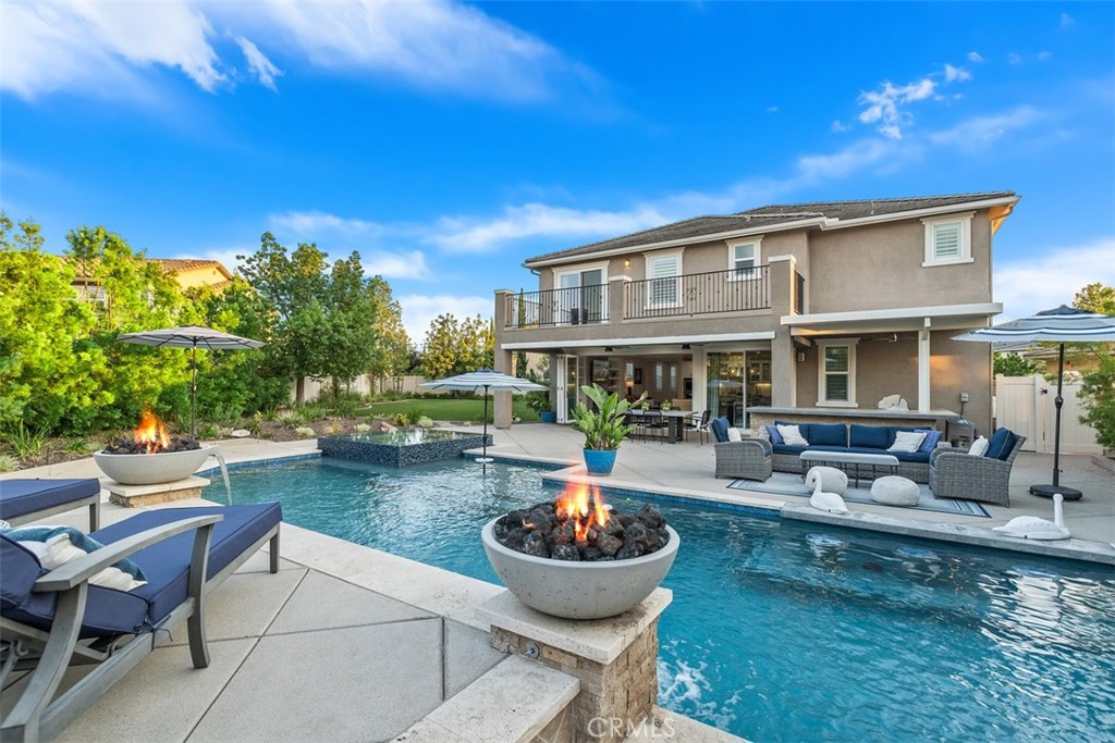 Offering over 4,400 sqft of luxury living with 5 bedrooms and 4.5 bathrooms, this stunning estate sits on the largest lot—over 1/3 acre—at the end of a cul-de-sac in the highly sought-after gated community of Roripaugh Ranch. From the moment you arrive, the curb appeal and custom design set this home apart. Inside, a private office just off the entry provides the ideal work-from-home setup or could easily serve as a 6th bedroom. A formal living room with soaring ceilings and a custom staircase creates an inviting and elegant first impression. Continue down the hall and prepare to be amazed as the home opens into a wide-open great room showcased by 16-foot bi-fold doors that bring the outdoors in. The chef’s dream kitchen features a massive quartz island, KitchenAid range, double ovens, built-in refrigerator, glass-front cabinetry, custom backsplash, butler’s pantry with wine fridge, and a Costco-sized walk-in pantry, all seamlessly connected to the informal dining and living spaces. The great room centers around a beautiful stone fireplace flanked by built-ins, setting the stage for luxury and comfort. Step outside to the entertainer’s paradise: a full-length California room with built-in BBQ overlooks the sparkling pool with raised infinity-edge spa, elevated tanning deck, and over 2,200 sqft of artificial turf with sprinklers for year-round enjoyment. At night, the backyard comes alive with dual fire bowls, a built-in fire pit, and Hollywood hedges creating a private wall of greenery. This home also features an attached second-generation suite with its own exterior entrance, offering a full kitchen with full-size appliances, sitting area, bedroom, bath, and in-room laundry—functioning as a true stand-alone apartment. Upstairs, you’ll find a spacious loft, three secondary bedrooms (one en-suite), and a luxurious primary suite with a private deck overlooking the backyard, spa-like bath with soaking tub, oversized shower, dual sinks, and an expansive walk-in closet. Additional highlights include 16 fully paid solar panels, energy efficiency, and access to Roripaugh Ranch’s country club-style amenities: clubhouse, 24/7 fitness center, pool, spa, tennis, basketball, pickleball, two parks, and private walking trails. This rare estate offers unmatched luxury, space, and lifestyle in one of Temecula’s most desirable communities.