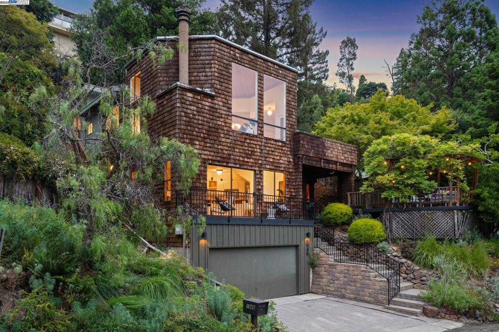 A peaceful and stylish retreat steps from Montclair Village, enjoy this updated contemporary 4BD/3BA featuring a full-service 1-bedroom apartment on a wide, usable lot. With dramatic over-sized windows, skylights, and several glass doors onto lush gardens, sunlight splashes across the 2621 SQFT home. A vaulted ceiling, views of the Oakland hills, a fireplace, and glass door to a deck make the living room a fabulous place to gather with family & friends both indoors and out. The spacious open floorplan enjoys a dining area, another fireplace and a sunny eat-in kitchen with new appliances and deck access. Drink your coffee in the breakfast nook with garden views or step on the deck for fresh air. The floor is complete with a bright bedroom and full bath. Upstairs find another bedroom, a full bath, and the wonderful primary bedroom with fireplace. Both bedrooms feature slat ceilings and sliding glass doors out to the magical gardens with plenty of room to relax and entertain. On the lower level, find the great 1-bedroom in-law unit with separate entrance and private balcony. The home also features bonus spaces, ample storage, 2-car garage, laundry room, and central AC. Nearby, a quick path to Montclair Village, Montclair Elementary, and East Bay Park trails.