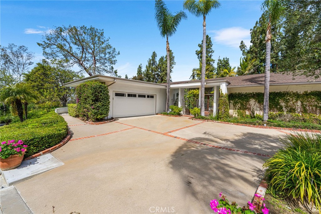 Located in the hills of North Tustin, this modern 1,963 sq. ft. home is a private retreat where sleek design meets natural beauty. A gated courtyard entrance welcomes you into the property, offering both privacy and charm before stepping inside. Floor-to-ceiling windows invite abundant natural light while showcasing the lush, expansive 13,950 sq. ft. lot, where mature trees and an elevated deck create a serene escape in your own backyard. Designed with a modern loft-inspired layout, the home seamlessly blends open-concept living with distinct, yet connected spaces. The kitchen flows effortlessly into the dining area, making it perfect for intimate gatherings or lively dinner parties. Soaring ceilings and oversized windows enhance the sense of openness, while clean architectural lines add to the home’s contemporary feel. Upstairs, two secondary bedrooms and a bathroom offer flexibility for family, guests, or a home office. Downstairs, the sprawling family and formal living rooms, anchored by a striking fireplace, provide the ideal setting for entertaining or unwinding. The primary suite is privately situated on the lower level, offering a tranquil retreat with easy access to the outdoor deck and nature-filled surroundings. Step outside and experience true indoor-outdoor living, where an expansive patio, lush greenery, and mature trees allow you to fully immerse yourself in the peaceful setting. This home offers a unique blend of privacy, style, and connection to nature. Located within walking distance to Arroyo Elementary and within the boundaries of top-rated Hewes Middle and Foothill High School, this home provides access to exceptional education in a highly sought-after neighborhood. Welcome home!