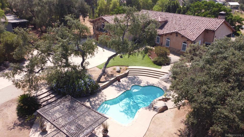"Variance granted for 2-4 Units". Beyond a private, gated entry lies a world meant for gathering, living, and dreaming. On a flat, useable acre framed by mature trees and golden westerly sunsets, three distinct residences create a rare multi-generational haven. The Tuscan-inspired main home, rich with high ceilings, 8-foot custom doors, earth-toned finishes, and sunlit spaces, invites you to linger—whether by the family-style kitchen with its granite island and black cabinetry, or fireside under the stars beside the newly built-in firepit. The permitted loft above the garage transforms into a chic studio rental, while the cottage-inspired front home offers two bedrooms, a warm fireplace, and a private walled patio. Between them, a pool house with bath and laundry stands ready for summer days beside the sparkling inground pool. With 7 bedrooms, 5.5 baths, and over 5,400 sq. ft. of living space, this compound offers 5 laundry facilities, 2 septic systems, paid-off 38-panel solar, paved RV parking with hook-ups, and an oversized driveway for endless guests. Wander the small orchard—avocado, grapefruit, lemon, lime, apricot—and imagine more. Here, life is secure, serene, and full of possibilities, where privacy meets connection in perfect harmony.