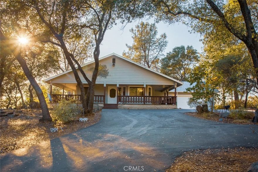 Nestled on a full acre surrounded by mature trees, this custom home blends rustic charm with modern comfort. Step inside the vaulted living room, where exposed beams, warm wood tones, and a wood-burning stove create a cozy yet spacious retreat. The floorplan offers both function and flexibility. A generous mudroom/laundry/pantry space off of the kitchen connects seamlessly to the garage, keeping daily life organized. The bedrooms are spacious, with the primary suite featuring a private bath and soaking tub for relaxing at the end of the day. Outdoors, a wraparound deck with built-in spa invites you to unwind or entertain while taking in the peaceful natural setting. Some highlights include a BRAND-NEW roof, central heating & air, and lots of storage. Additionally, there is separate living space with kitchenette, bathroom, and private entry with attached porch, making it a fantastic option for multigenerational living, guests, or rental income. Located on a quiet street among other custom homes, the property offers the perfect balance of seclusion and convenience—just minutes from town and the lake. With its one-acre parcel, versatile spaces, and timeless design, this home is ready to welcome its next chapter.