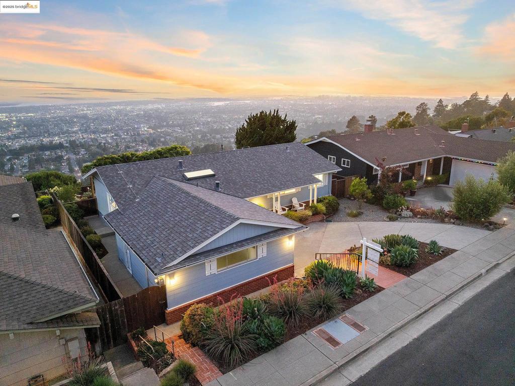 With sweeping views that stretch from the SF skyline and Bay Bridge to Mt. Tamalpais, this updated all-level home in the Oakland Hills offers a rare blend of simplicity, livability, and connection to nature. The circular floor plan encourages easy movement and effortless flow, with a wall of sliding glass doors that dissolves the boundary between indoor & outdoor living. A dramatic skylight crowns the kitchen, infusing the heart of the home with natural light and a sense of spaciousness, while custom built-in shelving in the living room adds function and architectural interest. Step out to a serene patio to discover a lush, mature garden sanctuary featuring flowering natives, sculptural succulents, twin bubbling fountains, and a romantic wisteria-draped arbor—an ideal setting for morning coffee or evening gatherings under the stars. Inside, the private primary wing offers a new en-suite bath with a glass-enclosed, zero-transition shower, custom tilework, dual vanity, and classic fixtures, creating a restful retreat that feels both elevated and timeless. Two additional bedrooms share an updated hallway bath featuring custom tile and an oversized LED vanity mirror. Owned solar+battery, newer roof, updated lighting throughout, and 2-car direct access garage. Close to 24, 13, & SF.