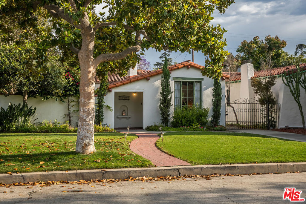 Discover timeless elegance in this captivating Spanish gem, rich with character and romantic allure. A red tile roof and graceful archway welcome you into a grand living room with wood beamed barreled ceilings, gleaming hardwood floors, a classic fireplace, and French doors opening to a serene courtyard with a trickling fountain. The formal dining room flows into a sunlit galley kitchen with stainless steel appliances and cozy breakfast nook, perfect for morning coffee. A cheerful pantry adds vintage charm and practicality. Four spacious bedrooms offer comfort and retreat, including a generous primary with en-suite bath with newly "penny" tiled floor. The luxurious guest bath stunning renovation has been recently completed. The 4th bedroom or versatile den/office connects to the expansive backyard with fruit trees, and a detached 2 car garage offers ADU potential and room for a pool. Set on a picturesque West Toluca Lake Street near the vibrant Toluca Lake Village cafes, restaurants, and shops. This home is a rare treasure. Homes of this character and soul are rare indeed. Come claim it before it is gone!