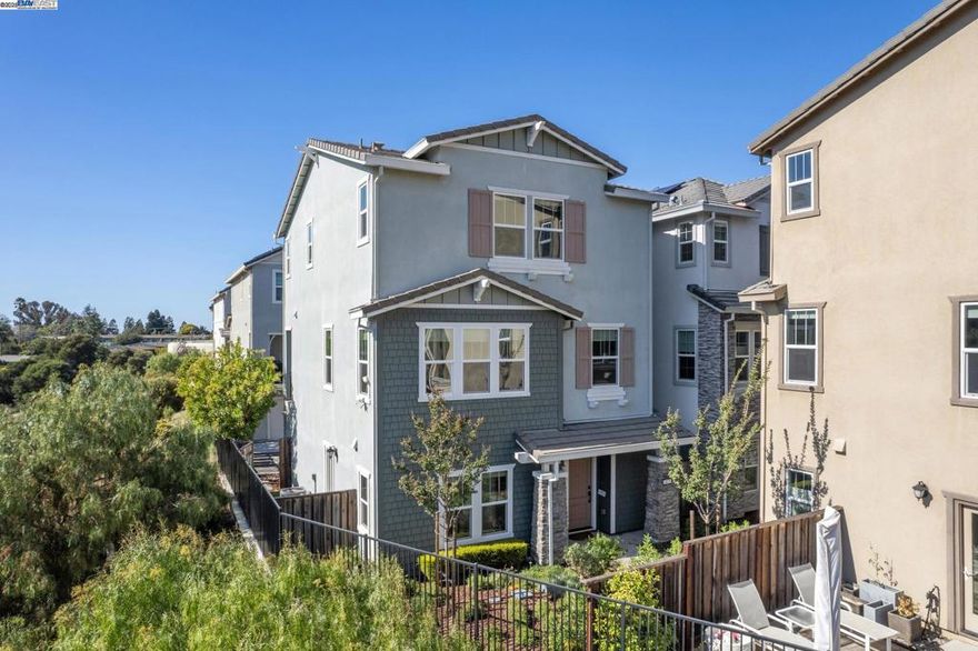 Privately positioned on a corner lot at the end of a quiet loop, this contemporary 3-bedroom, 3.5-bath single-family home blends modern elegance with peaceful hillside surroundings.  Built in 2020, the thoughtfully designed tri-level layout features a desirable en-suite bedroom on the lower level with direct access to the backyard, making it perfect for guests, multigenerational living, or a private home office. Upstairs, the main living area is drenched in natural light, highlighting the wide-plank floors and open-concept great room. The sleek kitchen features white shaker cabinetry, quartz countertops, a large island with bar seating, stainless steel appliances, and easy flow to a spacious balcony overlooking scenic canyon views.  Enjoy year-round comfort with multi-zone AC and heating, and savings with a fully paid solar system. The primary suite offers a serene escape with picturesque outlooks and a spa-like bathroom, while the secondary bedrooms are well-sized and bright.  Nestled within a newer community with no rear neighbors, this home is just minutes to local schools, parks, shopping, and major commuter routes—yet feels worlds away.