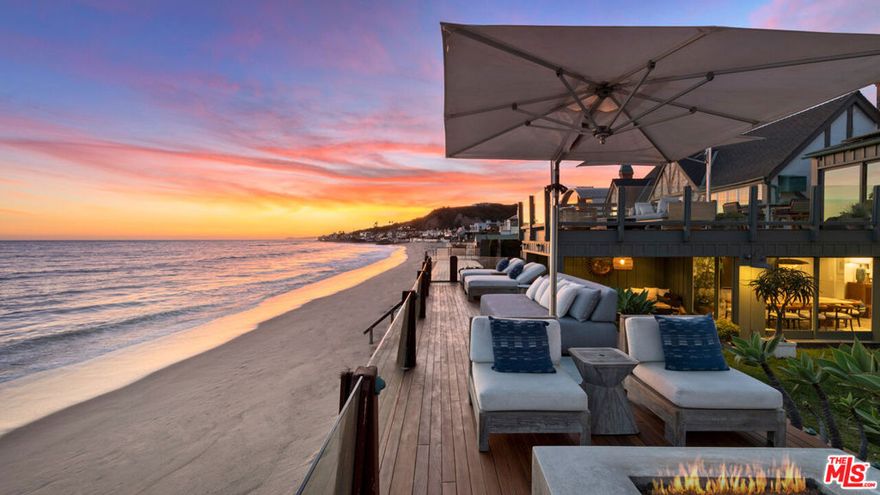 One of Southern California's most desirable addresses, this Cape Cod contemporary comprises a main residence and two guest houses with spectacular views and abundant space for indoor-outdoor living and entertaining. Set behind gates, the oceanfront compound has tall, wood plank ceilings, extra large windows, and wide doorways opening to tranquil patios, lawns, and beachfront decks on two levels.  In the main house, a light-filled great room with wood floors includes a spacious living area with a fireplace, a bar area, and a top-of-the-line island kitchen that will serve as the hub of any gathering. Extending from one side of the living room, the dining room has glass doors on two sides, one opening to a grand dining pavilion and the other to a private lawn and garden, also accessible from the living room. From this lawn, steps lead up to a wide beachfront deck furnished for relaxing and stargazing, with a hot tub, comfortable couches, a fire pit, a day bed, and steps to the sand. The views are sensational, from Point Dume to Palos Verdes, with island and ocean and gorgeous sunsets. The home has three bedrooms on the main floor, one, en-suite, currently used as a gym. Upstairs, the primary suite is a private getaway, with vaulted, beamed ceilings, a huge sitting area, a spa-style bath, and a floor-to-ceiling wall of glass that overlooks the lower deck and opens onto an upper-level oceanfront deck with majestic views. Separated from the main residence by a large lawn, the two guest houses are toward the front of the property. One has a living room, full kitchen, bathroom, and two bedrooms, plus a patio area with a sauna and firepit. Nearby is an additional structure that could be used as a yoga room, art studio, gym, or storage area. The second guest house is a large studio suite with vaulted ceilings, huge windows, ocean views, skylight, kitchenette, living and dining area, and a wraparound architectural sunroom. The home has covered parking for two cars, complete with a 220v plug, plus guest parking for five additional vehicles, as well as room for surfboards and other beach equipment. This is a wonderful, welcoming oceanfront home with vacation style and year-round comfort.