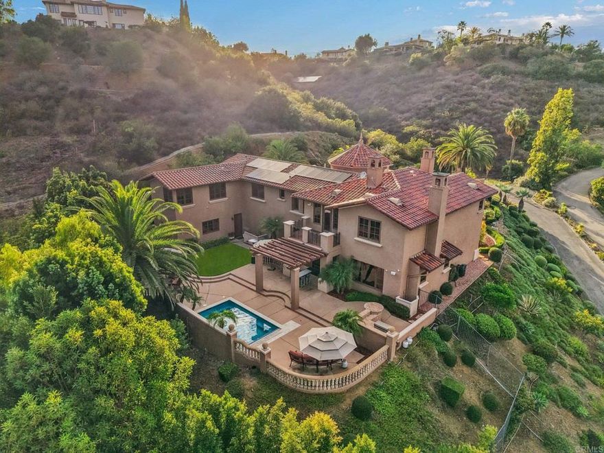 This private Mediterranean estate is set on an elevated 1.13-acre lot with sweeping mountain views at the end of a cul-de-sac in the prestigious guard-gated Cielo community within the highly sought-after R Roger Rowe School boundaries. Main residence offers 5 bedrooms, 3.5 baths, theater room, office, upstairs bonus room, along with an attached ADU that has a bedroom and bath. Grand driveway ascends to a circular motor court, where a meticulously landscaped yard and stunning fountain create a dramatic stage for arrival. Soaring two-story foyer with hardwood floors and a sweeping staircase welcome you. Formal living room has a fireplace framed by arched doorways, while the neighboring office is finished with custom built-ins. Kitchen features white cabinetry, a large center island, premium appliances, and daily dining that flows seamlessly into the family room with fireplace. Formal dining room and powder room complete the main level. Upstairs, primary suite offers a fireplace with raised hearth, private balcony, a spa-inspired bath with dual vanities, soaking tub, walk-in shower, and an expansive walk-in closet. Three additional bedrooms,  2-baths, laundry room, and bonus room complete the main residence. Attached ADU has a private entrance, full kitchen, living room, bedroom, and bath. Backyard is designed for entertaining with an oversized spa and cascading water feature, built-in BBQ island, fireplace, pergola, and multiple seating areas all surrounded by lush landscaping and mountain views. Entertainment continues with a private theater with separate exterior access. Additional highlights include 10KW owned solar system, 3-car garage, 2 tankless water heaters, EV charger, and wired for sound in select areas of the home with built-in speakers. Enjoy 24-hour guard-gated security, resort style amenities including a clubhouse, fitness center, pool, spa, tennis courts, pickleball, volleyball, basketball, & playgrounds.
