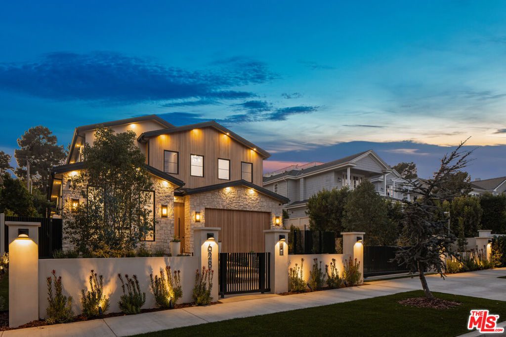 Emerging in Santa Monica's prestigious North of Montana neighborhood, an exquisite, newly completed residence by premier interior design and development firms 3D Construction and Elegant Luxury Homes, exemplifies refined coastal living. Spanning 7,692 square feet, the bespoke residence offers a rare blend of contemporary design, premium home tech, and wellness-focused amenities. A gated entry reveals lush landscaping framing a wood and stone facade, culminating in a commanding solid wood door that opens to reveal interiors of unmatched sophistication. The main level greets visitors with a floating staircase crowned by a cascading raindrop chandelier, setting the tone for the home's warm, artistic design. The formal living room centers around a floor-to-ceiling stone fireplace, while the adjacent dining room is lined by built-in cabinetry and wine storage. Throughout, a seamless blend of limestone, travertine, and marble is complemented by refined millwork and sculptural lighting fixtures, enhancing the home's luxurious atmosphere. The chef's kitchen is both functional and striking, with dual stone-topped islands, illuminated glass cabinetry, and ceiling-height stone backsplash. Professional-grade Wolf and Sub-Zero appliances, dual ovens, and dishwashers enhance the space. A butler's pantry, temperature-controlled wine fridge, and built-in espresso machine add further convenience and sophistication. Upstairs, the primary suite is a serene retreat, boasting vaulted ceilings, a statement fireplace, private balcony, and an expansive custom closet. While the spa-like primary bath offers dual vanities, a steam shower, and a soaking tub, alongside a coffee bar, transforming daily rituals into moments of respite. Two additional ensuite bedrooms and a laundry room complete the upper level. A haven for wellness and leisure, the lower level features a gym and spa suite with a steam room and sauna. A theater, recreation room, and full-service bar create the ultimate entertainment space, all with access to an outdoor patio with stairs directly to the backyard. Two ensuite bedrooms and a second laundry room ensure comfort for guests or staff. Outside, the grounds are a private oasis, with mature hedges framing a resort-inspired pool and spa, complete with a waterfall feature and automatic cover. A built-in outdoor kitchen and covered patio with surround sound provide the ideal setting for al fresco dining and gatherings. Modern conveniences include an elevator servicing all levels, Control4 home automation, Nest climate control, and a two-car garage. Situated moments from Montana Avenue's boutiques, San Vicente's tree-lined streets, the Brentwood Country Club, and Santa Monica's coastline, this residence epitomizes Westside living at its finest.