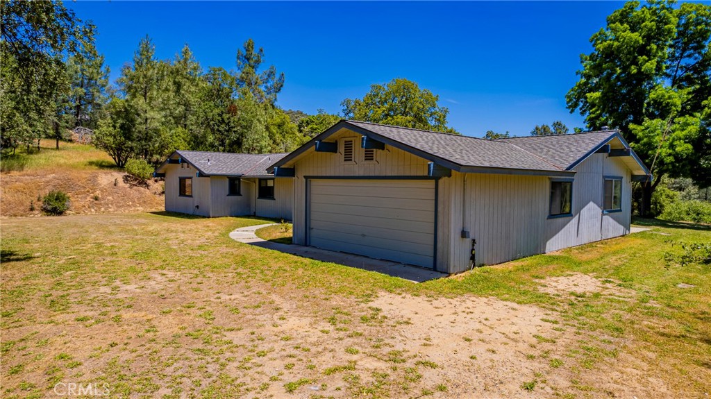 Tranquil Country Home on 19.17+/- acres – Near Yosemite National Park and Bass Lake. Discover the beauty of nature and modern comfort in this 2,151+/- sq. ft. single-story home, nestled amongst scenic land. Surrounded by White, Black, and Blue Oak trees, towering Pines, and lush Manzanita bushes, this private retreat offers majestic views of the Sierra National Forest and features its own underground spring for a true sense of tranquility. Steeped in history, this property sits on a historic road once traveled by early pioneers on their journey to Yosemite Park, just 16 miles north. Located only 8 miles from Oakhurst and 7 miles to Bass Lake makes this the ideal location property. Inside, the spacious "Great Room" layout seamlessly connects the kitchen, living room, family room, and dining area with a breakfast bar, perfect for entertaining and everyday living. The kitchen boasts ample oak cabinetry and generous counter space, making meal prep a breeze. The home features 4 bedrooms, including walk-in closets in both the bedrooms and the hallway. A Jack-and-Jill bathroom connects 2 bedrooms, while the property includes 3 full baths for ultimate convenience. The high ceiling and bay window in the family area adds to the airy and inviting feel of the home. Sliding doors invite you to the outside patio to enjoy the amazing views while taking in the cool breeze. A wood stove in the family room keeps you warm year-round, fueled by an endless supply of wood from your own land. The home also includes a new HVAC system, a whole-house fan, and an evaporative cooler, ensuring comfort in every season. Additional highlights include your very own private well with a storage tank, a greenhouse set with hydroponics, RV parking w/hookups, and plus an oversized attached garage for storage and parking. There is an added detached garage perfect for a workshop space along with part of the land divided across the street. This home blends privacy, history, and modern amenities in one exceptional package with lots of potential. Don’t miss your chance to own this one-of-a-kind retreat near Yosemite!