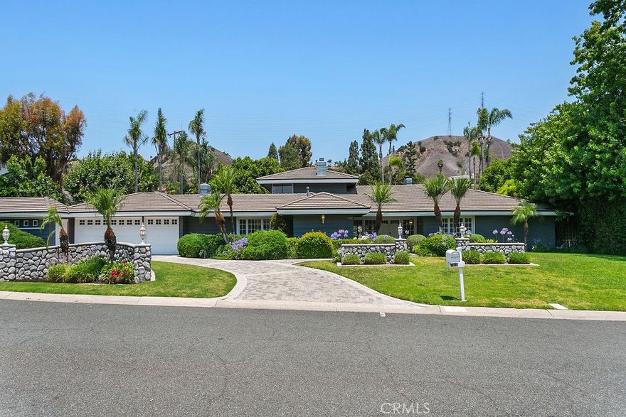 Your luxury dream has arrived with this sprawling Villa Park estate. Tucked away in the private rolling hills of Villa Park, this home has the perfect blend of traditional feel and modern utility. Situated on an expansive half-acre lot and featuring river rock hardscape, lush landscaping, and a circular driveway, the property offers stunning curb appeal and an unforgettable first impression. Step through custom, side-lit double doors into a light-filled and functional entryway.  Soaring cathedral ceilings, trendy hardwood floors, and an expansive living room view set the tone immediately. The living room has an impressive custom finished fireplace framed with built in shelving and hutches on either side. French Doors along the back give this entry experience a light and airy feel. Kitchen is a culinary dream with moveable butcher island, custom two-tone cabinets, quartz counters, farm sink, walk in pantry, SS appliance package, and views of the sparkling pool. The kitchen also boasts a custom-built in hutch with glass inlaid uppers, and plenty of room for a kitchen nook table. Family room is once again, spacious and cozy with cathedral exposed beam ceiling details, white block finished fireplace, wainscotting, built in wet bar, hardwood floors and French door wall with views of the sparkling pool and spacious backyard.  The primary bedroom is open and inviting with brick finished fireplace, French door wall, and access to a resort like primary bath. The primary bath is complete with spacious walk-in closet, custom cabinets, dual vanity, cosmetics counter, floating shelves, walk in shower, and bath yard access for after swim washes. Secondary baths have been finely appointed with custom cabinetry, massive soaking tub, elegant hardware and faucets finishes, and dual vanity sink in hall. This home lives like a true single story with all living area on the main level. It does enjoy a second story bonus room with a private balcony and stone finished fireplace. The dining room is such a treat with elegant ceiling detail, rear location for privacy, and oversized windows for plenty of light and scenic exterior views. The backyard is your own peaceful retreat complete with lush, manicured landscape slope, sparkling pool, raised deck, firepit, and quiet tranquil atmosphere. Other features include ceiling fans, spacious 3 car garage, huge attached and covered storage area, cathedral ceilings in common areas, idyllic quiet location, spacious laundry, and so much more!