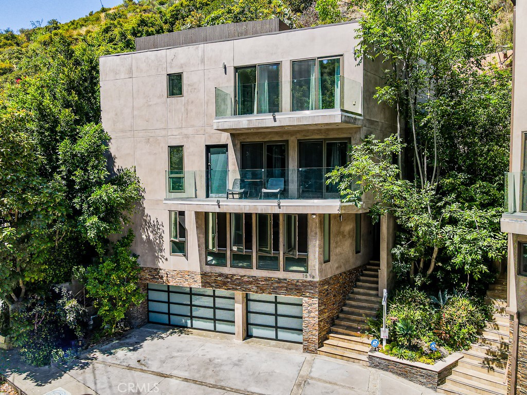 This stunning contemporary home is a dream come true for modern entertainers. Located just above Sunset Blvd, this lower Bel Air/Holmby Hills masterpiece features a large rooftop terrace and freestanding units with a 3-car garage for convenient parking. With its architectural flair, this home offers 4020 sq. ft. of luxurious living space. Inside, you'll find three bedroom suites, a den, and six bathrooms. The open layout gives you views from nearly every room, and fills the living space with natural light along with a work-space and sitting area. Each floor can be accessed via an elevator from the 3-car garage. The home also boasts multiple balconies, offering gorgeous canyon views. The open floor plan seamlessly connects the custom kitchen, complete with Viking appliances, walk-in pantry, and quartz counter tops, to the family room. Natural light floods the space, highlighting the stone and hardwood floors, while a large balcony and powder room add even more functionality. State-of-the-art amenities, including automated smart home technology with surround sound throughout and security cameras to ensure that this home is truly an entertainer's dream. Bonus: enclosed garage storage area not included in sq footage. *A few photos have been virtually staged to highlight the home's possibilities and flow.