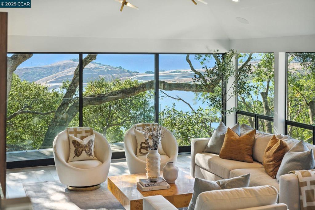 This modernist retreat, rebuilt from the studs in 2019, is set on a private lane just a mile from top-rated Sleepy Hollow School. It offers architectural distinction and a seamless connection to nature, with views of Briones and the hillsides beyond. Mature trees surround manicured gardens and a grassy play area. The open-concept kitchen (with elite appliances) and dining room sit under elevated ceilings. A waterfall island, nearly 80 sq ft, provides bar seating for 5, and the adjacent dining room seats 10–12. A glass wine cellar showcases 180 bottles. Sliders open directly to the deck, where gas heaters ensure year-round comfort. The living room offers a sleek fireplace and oversized windows. The office near the entry hall makes work from home easy. (The room could be reconfigured as a nursery or 5th bedroom.) The principal suite offers 2 private decks and a bathroom featuring Porcelanosa tile, marble floors, dual vanities, an oversized shower and panoramic outlooks. The closet accommodates any wardrobe. Two more bedroom/bathrooms are upstairs. Between them lies the movie studio, certain to be the gathering place for entertainment of family and guests. The 4th bedroom suite, downstairs, is accessed by a private entrance and is ideal for an au pair, in-laws, or guests.
