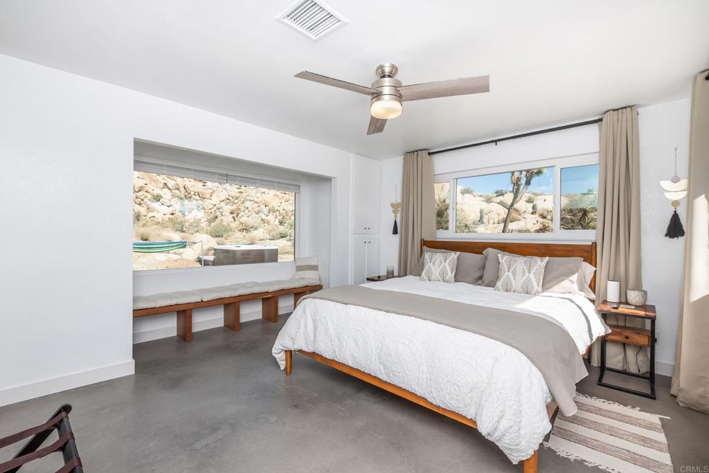 Desert Retreat with Breathtaking Views and Modern Upgrades Welcome to your private desert sanctuary in the heart of Yucca Valley. Nestled among stunning natural boulders, this beautifully remodeled home offers unmatched privacy, dramatic scenery, and endless opportunities for relaxation and stargazing. Just a short 10-minute drive to Joshua Tree National Park, this property combines modern comfort with the magic of desert living. Step inside to find a thoughtfully upgraded interior featuring a brand-new roof, new AC, fresh paint, new flooring, countertops, refrigerator, and dishwasher. The open living room, anchored by a cozy fireplace, flows seamlessly into the kitchen, creating an inviting space for gathering. A separate den is perfect as a theater room or flexible living space, while a dedicated office complements the three spacious bedrooms. The primary suite boasts a large picture window framing the boulder-studded backyard and a spa-like bathroom with a clawfoot soaking tub. An additional full bathroom with tub and shower continues the modern design. Outdoors, tranquility awaits. The expansive backyard—completely private and unseen by neighbors—features awe-inspiring boulder formations, twinkling city-light views, and a hot tub tucked among the rocks for the ultimate stargazing experience. Whether you’re enjoying desert sunsets, relaxing under the night sky, or hosting friends, this setting is one of a kind. Additional highlights include a detached two-car garage and a sliding glass door that opens to the serene backyard retreat. This is more than a home—it’s an experience. Don’t miss your chance to own a rare, fully upgraded desert escape with iconic Yucca Valley views.
