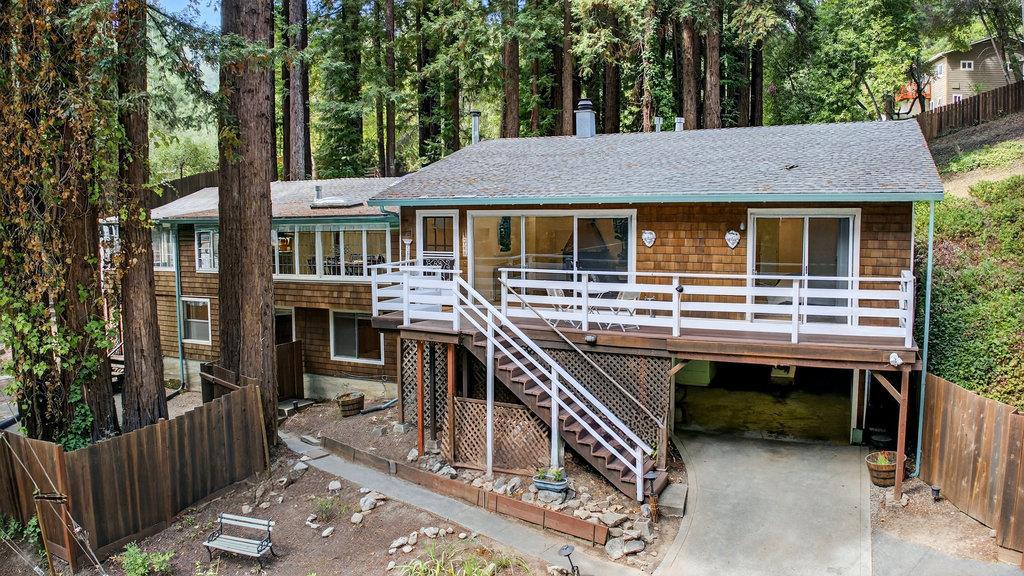 Live the life of your dreams at this Mountain Retreat! This inviting home sits on a peaceful, park-like 0.65-acre parcel surrounded by majestic redwoods. The main level offers 5 comfortable bedrooms and 2 bathrooms, while the lower level features a private 1-bedroom, 1-bath guest suite with its own entrance, perfect for loved ones or extended stays. Inside, the charming kitchen opens to the living and dining areas, anchored by a cozy wood-burning stove. Three skylights and an abundance of windows enable light-filled spaces and bring nature views. Artistic touches include stained glass, knotty pine and a stone accent wall. A bright sunroom flows onto the sun-filled back deck,perfect for gatherings, while a welcoming living room with fireplace and sliding doors opens to the sunny front deck. Outdoors, enjoy a fully fenced yard and your very own redwood grove, offering both sunny and shaded retreats.Plenty of room to garden, set up a play structure or meander through the woods.Parking for 4 cars, plus 2 ample sized storage/utlity rooms allow space for a workshop or other projects. Just minutes to downtown Boulder Creek for shopping and dining, with an easy commute to Silicon Valley. This home brings the best of both worlds by blending mountain serenity with everyday convenience.