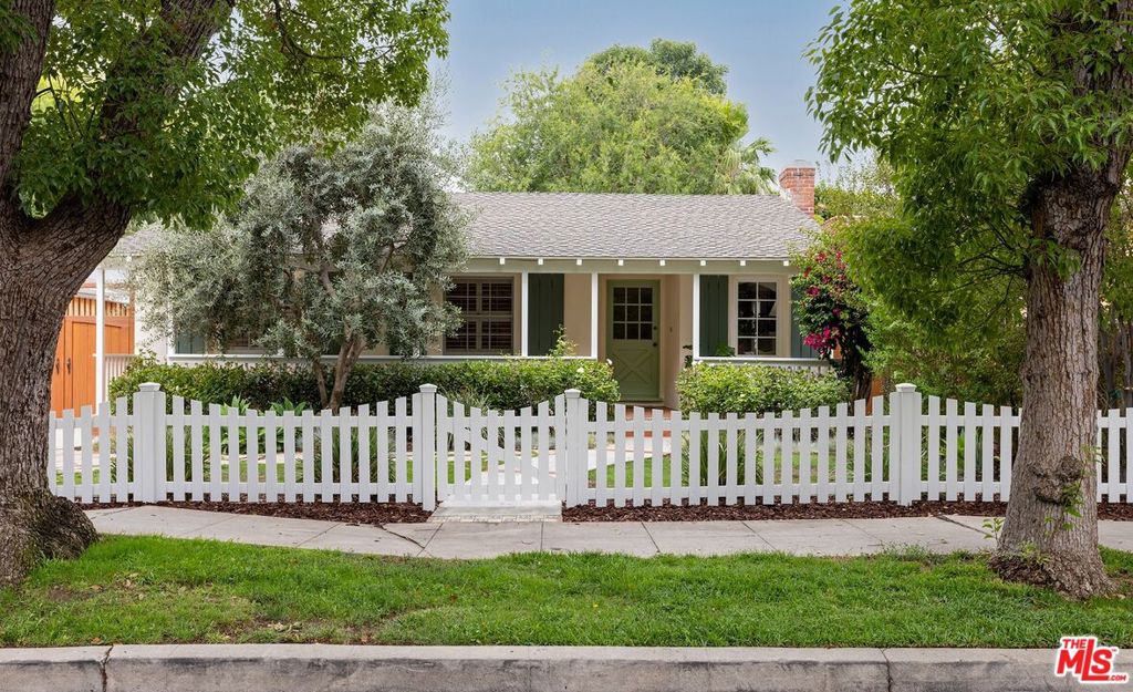 Enchanting traditional home with classic white picket fence, situated on a picturesque tree-lined street in coveted Sherman Oaks. This charming residence with over 1,500sf sited on a generous 6,752sf lot offers a private garden sanctuary professionally landscaped by Sacred Space as featured on the T.V. show Interior Motives. A light-filled living room with cozy window nook and fireplace flows seamlessly into a dedicated dining area. Playful retro kitchen features bespoke flooring, tiled counters, and breakfast bar. The spacious family room with vaulted wood-beamed ceilings, brick fireplace and custom built-ins opens to the whimsical backyard, creating a perfect layout for indoor/outdoor entertaining. Dine outdoors in a magical vineyard-inspired setting under the grand wood pergola or lounge in one of the multiple outdoor living areas framed by mature trees and privacy hedging. Separate storage shed and detached garage with driveway parking offers ADU potential. This lovingly maintained home is ideally located near top-rated schools, shops and restaurants, and commuter-friendly access. Whether you're looking to move in, update, or expand, this is a rare opportunity in a highly sought-after Sherman Oaks neighborhood.