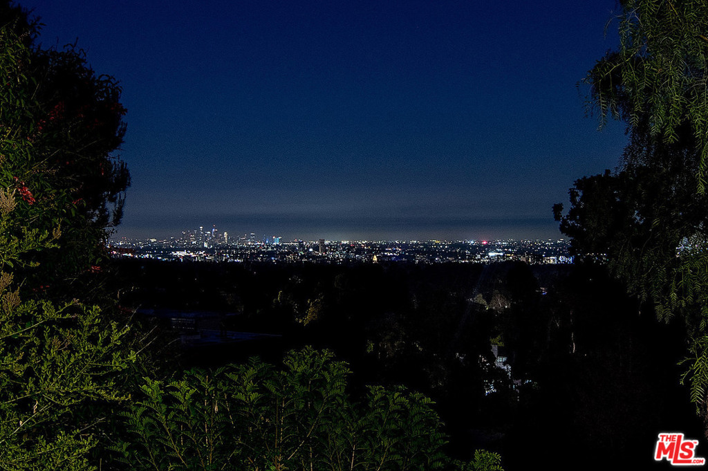 This extraordinary Balinese-inspired estate is situated on apx. 1.43 acres in prime Lower Bel Air. Perched on a promontory overlooking panoramic city views, this property offers a secluded & tranquil resort-style setting. Private gates lead down a long private driveway to a large motorcourt & 3-car garage. The double-doored entry is flanked by a lush lily pond. The formal foyer leads into the magnificent great room. Arranged in an open floor plan under a main pavilion w/soaring ceiling & an intricately-designed structure of beams, the great room combines the living rm, family rm, den, & formal dining rm. Walls of glass throughout open to the lush exterior & welcome the shimmering city views. Large chef's kitchen w/professional appliances & over-sized butcher block island. The master suite is spacious yet intimate, w/seating area, fireplace & spa-like bathroom. Three additional bedrooms. The private & verdant grounds are complete with lawn, pool, fountains, & meandering paths.