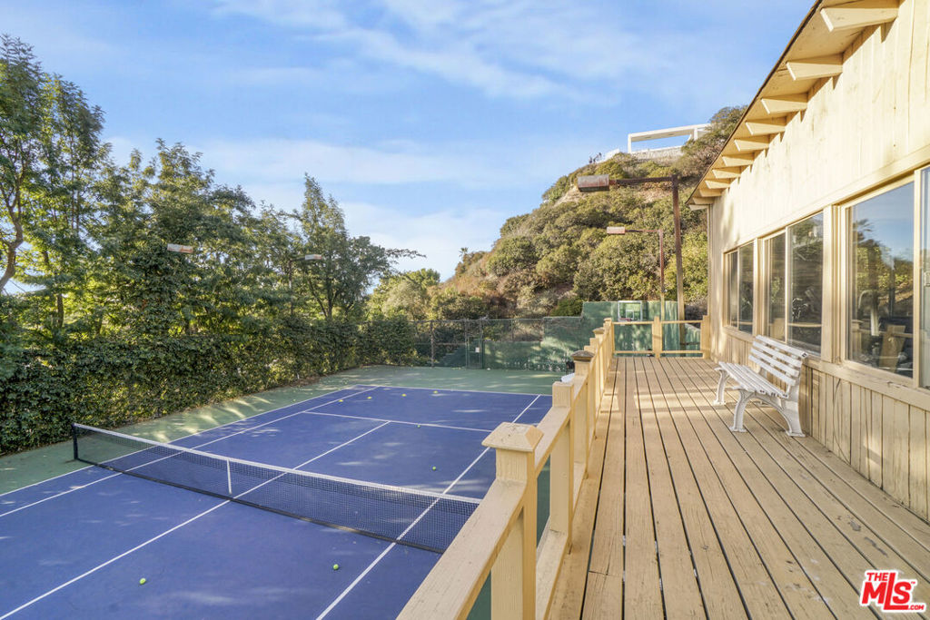 Rare Tuscan Villa with Tennis Court in Prestigious Trousdale Estates. This exceptional 0.66 acre property combines the timeless elegance of a single-story Tuscan villa with the rare luxury of an oversized professional-grade tennis court. The 5,081 sq. ft. At the heart of this estate is an exquisite single-story Tuscan villa spanning 5,081 sq. ft., blending timeless Mediterranean charm with modern sophistication. The home boasts 4 ensuite bedrooms, 6 bathrooms, and a welcoming gated driveway leading to a 3-car garage with ample additional parking. Upon entering, you are greeted by a grand foyer adorned with intricate crown molding and sparkling chandeliers, setting a tone of elegance and refinement.The open floor plan, complemented by French doors throughout, invites natural light into the home, enhancing its seamless flow and bright, airy ambiance. The state-of-the-art chef's kitchen, outfitted with top-tier Thermidor appliances, features 1,200 sq. ft. of marble and limestone countertops, centered around a striking blue Caesar stone island. Adjacent to the kitchen, a formal dining room, wet bar, and wine cellar make this home a true entertainer's dream.The luxurious master suite offers the ultimate retreat, complete with an office overlooking the backyard and pool, as well as separate his-and-her walk-in closets. The spa-like bathrooms feature double sinks, a steam sauna, a vanity, and serene garden views. Two additional spacious ensuite bedrooms and a guest suite with direct access to the pool and backyard ensure comfort for family and guests alike.The outdoor grounds are nothing short of spectacular. A sparkling pool, sundeck, and lush landscaping provide a serene escape, Perfect for both avid tennis enthusiasts and large-scale entertaining, the court is detached from the main house, ensuring privacy and versatility. With a fitness center perched above, it offers a space for recreation and exercise without disrupting the serenity of the main residence. This multifunctional property epitomizes the best of Beverly Hills luxury living, offering privacy, elegance, and convenience, just moments from Rodeo Drive and world-class dining and shopping.
