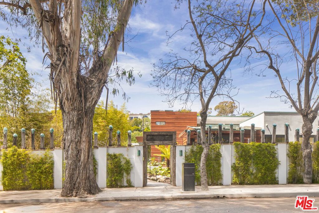 The impressive innocuous wall enclosing the compound gives only a slight hint of the Pura, "White Lotus" vibe behind it. When entering through the repurposed 500 year old Monastery gates one is immediately immersed into the harmony of the environment. The recently completed landscaping under the supervision of JohnstonVidal, perfectly compliments the interior spaces. Built almost entirely of organic material, including teak wood throughout and limestone, the house perfectly blends with the nature providing a deep rooted familiar grounding. The house offers two main beyond your imagination with the most impressive closet, bedroom suites plus three additional bedroom suites The current interior footprint of generous spaces allows for flexibility of adding more sleeping quarters. The breathtaking public spaces including the living room, dining room and open kitchen family room form a courtyard creating an interior/exterior space reminiscent of a five star lounge and pool space. The environment telegraphs a calming atmosphere by blending classical and traditional styles without sparing on any modern amenities such as solar and power pacs potentially supplying several weeks of off grid power. The house is placed on a double street to street lot and includes a three car garage that will make you smile. The house combines a pleasing Balinese aesthetic with thoughtful precise functionality. Originally the house was designed by Sorensen Architects following the LEED certification guidelines. In the past the premises have been enjoyed and have been a creative fountain for the likes of Charlie Chaplin & Sam Francis.