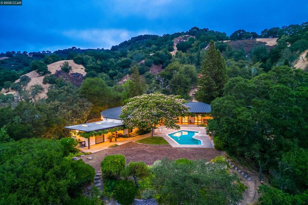 Situated atop a private 2-acre knoll and embraced by stately oaks, this custom Mid-Century Modern gem is a rare offering in the heart of Lafayette’s coveted Happy Valley. Designed for seamless single-level California indoor-outdoor living, this unique home celebrates light and nature with timeless design. The floor plan offers 4 bedrooms, including a private master retreat with office and deck, a guest suite, and 3.5 baths with the majority of rooms opening onto the tiled loggia. Step outside to a sparkling pool and patio perfect for relaxation or entertaining, an extensive level yard and the vistas beyond. Evening breezes flow easily and deer and birds frequent the property. A detached structure with storage/wine cellar expands possibilities for work, fitness, or creative pursuits. With easy access to top-rated Happy Valley Elementary, BART, Lafayette’s vibrant retail, and miles of hiking adventure at your doorstep, this residence offers not only striking architecture and privacy but also fantastic convenience!