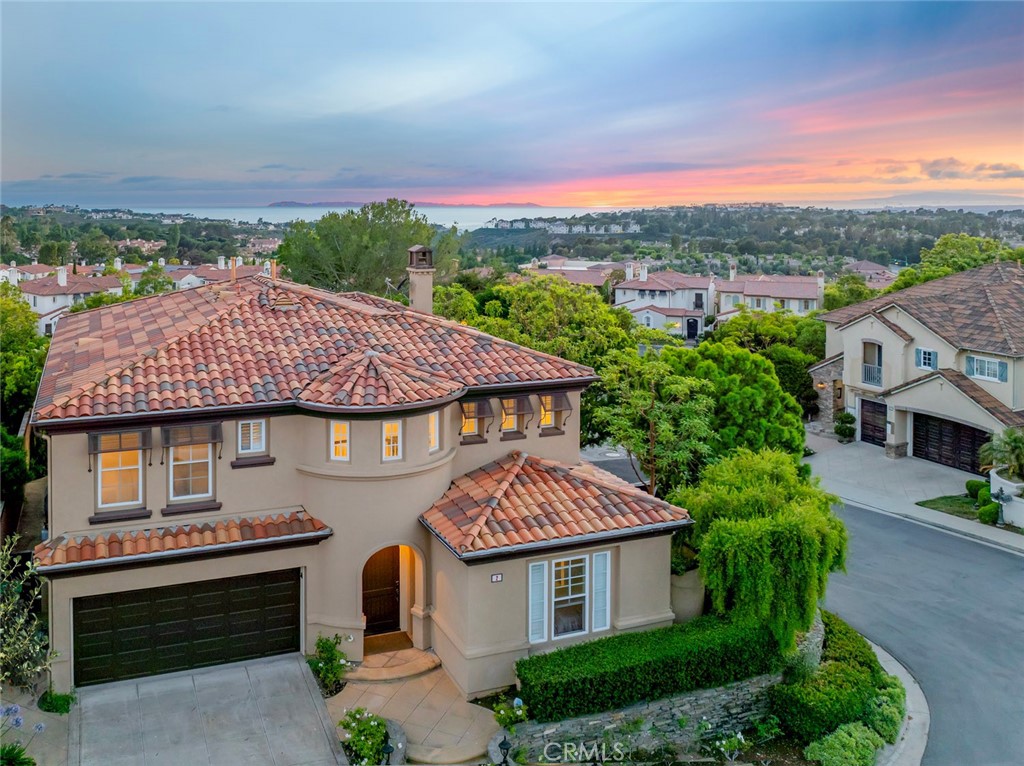 Elevated on a private corner lot in one of Newport Coast’s most sought-after communities, this Tesoro Crest residence pairs stunning ocean views with an open, light-filled layout. Enjoy views of downtown Long Beach and Catalina Island, with a wraparound yard that offers multiple areas for entertaining, relaxing, and taking in the ocean breeze. Step inside to soaring two-story ceilings and an abundance of natural light that immediately set the tone. The formal living and dining areas greet you upon entry and flow effortlessly into the kitchen and great room, creating a seamless layout ideal for everyday living and entertaining. The kitchen features Calacatta gold marble countertops, a center island with bar seating, and top-of-the-line stainless steel appliances, all framed by walls of windows that bring the outdoors in. Ideal for multigenerational living or guests, the main level includes a bedroom and bath. Upstairs, the expansive primary suite offers a spa-inspired bath with a soaking tub, walk-in shower, dual vanities, TWO walk-in closets, and a private balcony where ocean and sunset views steal the show. Two additional bedrooms and a dedicated office, or bedroom five, complete the upper level. Tesoro Crest is the only neighborhood in Newport Coast with direct pedestrian access to the award-winning Newport Coast Elementary School. Residents also enjoy exclusive access to the community pool and spa, along with Coastal Canyon Club amenities including a Jr. Olympic pool, towel service, tennis, basketball, and social events.