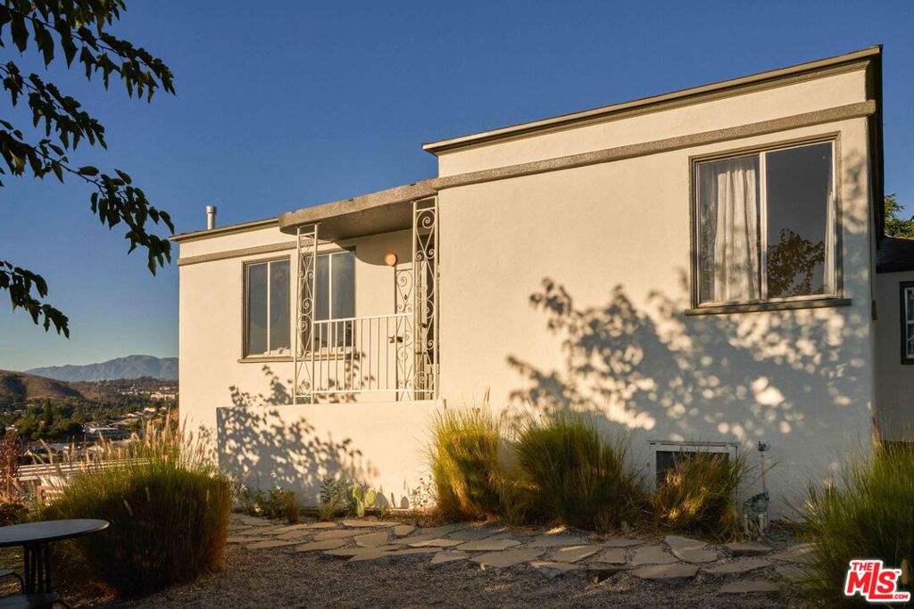 1940s traditional in University Hills with mountain and skyline views. Perched above the street, this 3-bedroom, 2-bath home has an impactful presence with its Streamline Moderne elements of strong horizontal lines and a curved overhang. Although the home is on a hillside, there's ample flat and usable areas to enjoy the Southern California sun. Approaching the home, you are greeted by a front yard with drought tolerant plants screening you from the street, native grasses and flowering mallow plants. The connection to the outdoors continues inside with a direct sight line to the backyard and numerous windows flooding the rooms with light and captivating skyline views. The kitchen has been thoughtfully redesigned and features new cabinetry, appliances and stainless steel countertops. The adjacent dining area is cozy with a wood banquette seating area. At the opposite end of the home are the bedrooms and two updated bathrooms with a warm neutral palette and timeless materials like marble and travertine. Flowing easily from the kitchen, is an oversized glass door that leads to a private back patio space. To the side of the house is a detached studio - perfect for a home office or creative pursuits. There's additional outdoor space for dining or lounging that overlooks the majestic San Gabriel mountains. When not enjoying your peaceful hillside home, you are only moments from local favorites like lil'East Coffee, Tirzahs Mexi-Terranean, Evil Cooks, Artemisia Nursery, Los Dorados LA, Correas Mariscos & Cocina, Holy Grounds Coffee + Tea or a short drive to other hip east side neighborhoods. If you are looking for a well designed hillside house with great outdoor space and views, this is your spot!