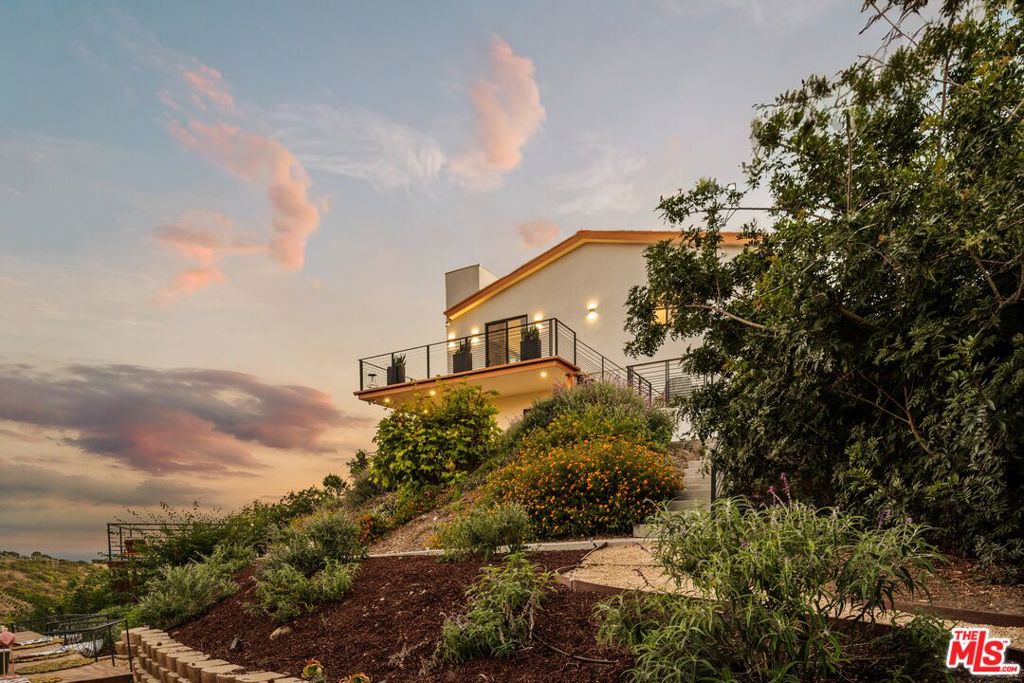 Commanding a private acre above Malibu's storied coastline, this newly reimagined retreat completed in August 2025 balances cutting edge design with natural warmth, creating a residence that is both sophisticated and serene. Walls of glass frame sweeping ocean and mountain vistas, while rich materials, from natural hardwoods to Porcelanosa finishes, add depth and texture to the expansive interiors. The home unfolds across 2,577 square feet, featuring an open concept layout designed for both effortless entertaining and intimate living. The Bauformat kitchen, outfitted with Miele and Fisher & Paykel appliances along with a striking marble island, anchors the main level, flowing seamlessly into the dining area. A dramatic living room, defined by a commanding fireplace, custom lighting, pitched ceilings and a Plum wine dispenser, blurs the boundary between indoors and out, spilling onto terraces that capture the full breadth of Malibu's landscape. The primary suite serves as a private sanctuary, including a bespoke walk in closet and a spa-inspired bathroom. Custom vanities, gold accents, and a freestanding soaking tub create a space of pure retreat, with uninterrupted views stretching to the horizon. Two additional bedrooms echo this ethos of light and openness, offering comfort and privacy. The lower level extends the home's capacity for leisure and entertainment, with an added powder room, lounge area, and direct access to the outdoors. Throughout, thoughtful details, from elevator access to custom storage solutions, underscore both luxury and functionality. Beyond its walls of glass, the home reveals an outdoor setting designed for the Malibu lifestyle. Expansive decks, multiple seating and dining areas, and mature landscaping ensure both privacy and connection to nature. Whether hosting under sunset skies or savoring quiet mornings, the setting seamlessly merges architecture with landscape. Just moments from the world class beaches of Point Dume, this property is a testament to modern coastal living, offering an unparalleled fusion of privacy, design, and location.