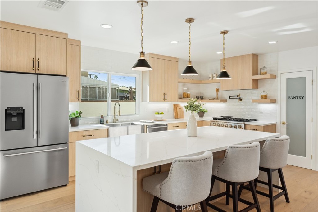 This completely redesigned and remodeled single-story home offers luxurious finishes throughout. Hard wood floors greet you as you enter the living area of a light and bright open floor plan. Enjoy dinners in your lovely dining room, conveniently situated next to the kitchen. This kitchen screams sophistication with sleek flat panel cabinets, quartz countertops, a walk-in pantry, 9 ft. waterfall island with chic pendant lights, a stunning backsplash, and stainless-steel appliances that are all included! Relax in the living room featuring an eye-catching accent wall and french doors with access to the backyard. Down the hall is a powder room and a separate laundry room with a washer, dryer and ample cabinet storage. This home offers 4 bedrooms including 2 primary suites, all with direct bathroom access. The first primary suite is the largest with french doors that open to the backyard, and an ensuite bathroom that is to die for. This bathroom has elegant tilework throughout, a dual sink flat panel vanity with quartz countertop, free-standing tub, magnificent walk-in shower, and a spacious walk-in closet. The second primary suite has a unique fireplace, preserving a piece of the home’s original charm. Its ensuite bathroom has a beautiful tile walk-in shower, tile floors, and a flat panel vanity with quartz countertop. A Jack & Jill bathroom sits between the 2 remaining bedrooms with an alluring accent wall, flat panel dual sink vanity and a divinely tiled tub/shower. A detached garage is at the rear of the home and is equipped with an electric car charger and epoxy floor and can be converted to ADU. The backyard has a new deck and enough room for kids/pets to play comfortably. This property is as close to a new built home as you can find, taken down to the studs and completely refinished (with permits). Come fall in love with it today!