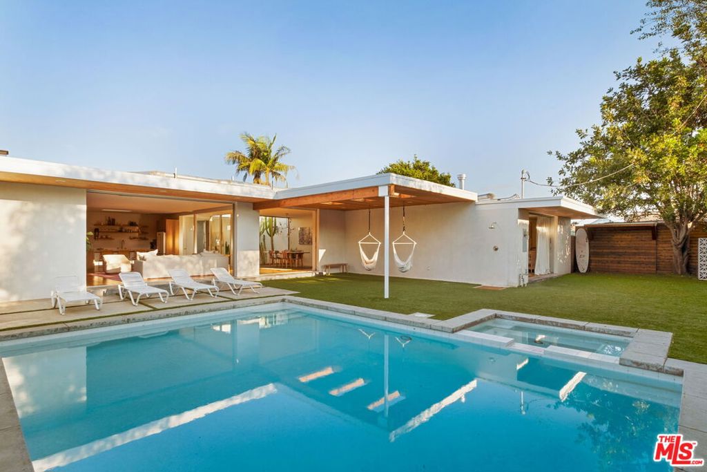 Make all your Mid-Century dreams come through at this spectacularly remodeled Palm Springs Modern located in one of the most manicured neighborhoods in all of LA. Meticulously reimagined with the utmost care, the owner painstakingly preserved the original mid-century details of the home such as the glass-walled entryway atrium and the sunken tub and rain shower in the primary suite, while also modernizing to today's standards with wide plank oak floors, floor to ceiling Fleetwood sliding glass doors, and the perfect open floor plan that maximizes indoor/outdoor flow. Set on a compelling, over-sized 9,000 square foot lot and combined with a gated entryway courtyard, the property has a private compound feel. A formal entryway with the original terrazzo floors leads you to the state of the art kitchen, which is highlighted by an onyx waterfall style island, custom cabinetry, floating shelves, and a stylish Cafe fridge. The kitchen and breakfast nook open into the sundrenched formal dining room and the spacious living room that features the original rock-clad wood burning fireplace. These rooms effortlessly open onto the wood-paneled covered patio and into the backyard, who's mature hedging provides privacy to the sparkling pool and spa and is the perfect setting for entertaining. The sumptuous primary suite features more floor to ceiling Fleetwood sliding doors that open to the backyard, a row of double door closets provide ample storage, and a gas fireplace adds to the stunning ambiance of the space. The primary bathroom is a sight to behold with a custom dual vanity, sunken terrazzo tub, giant overhead rain shower, and a second atrium that floods the space with light. Three additional good-sized bedrooms and one and a half bathrooms round out the home. Additional highlights are the walk in pantry, laundry room with room for a dual washer and dryer, and a spacious 3 car garage that is ideal for your car collection or additional storage. This thoughtful, stylish home is a unique find, all while being in a quiet location that is an 8 minute drive to the beach, with easy access to the 405, Culver City, Beverly Hills, and LAX.
