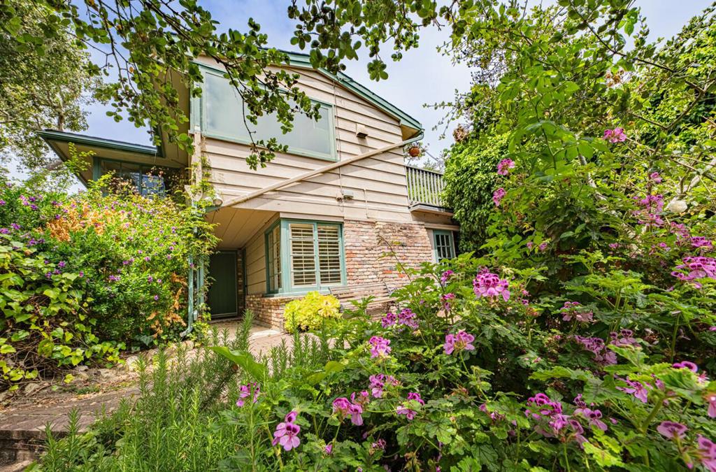 Tucked away in a private cul-de-sac in the heart of Carmel Village, this enchanting cottage is ready for a new owner to restore its timeless charm. Highlights include rich hardwood floors, open-beamed ceilings, and a grand brick gas fireplace, adding warmth and character to the living space. The kitchen and breakfast nook are bathed in natural light thanks to a wall of windows overlooking the picturesque backyard and the serene beauty of nature beyond. Upstairs, the primary bedroom offers a peaceful retreat with an attached private bathroom, creating a thoughtful separation of space. Downstairs, a secondary living area features two bedrooms, a full bathroom, and a sunlit room with its own cozy fireplace. A separate utility room leads to a delightful brick patio where steps wind down to a charming art studio perfect for creative inspiration. Ideally located within walking distance of downtown Carmel, Mission Trail Park, and the beloved Outdoor Forest Theater, this property offers both tranquility and convenience. With easy access to Carmel High School, the Barnyard shopping center, and tall the treasures of Carmel-by-the-Sea, the best of the Peninsula is just moments away. Appraisal $1.9Million (June 2025)